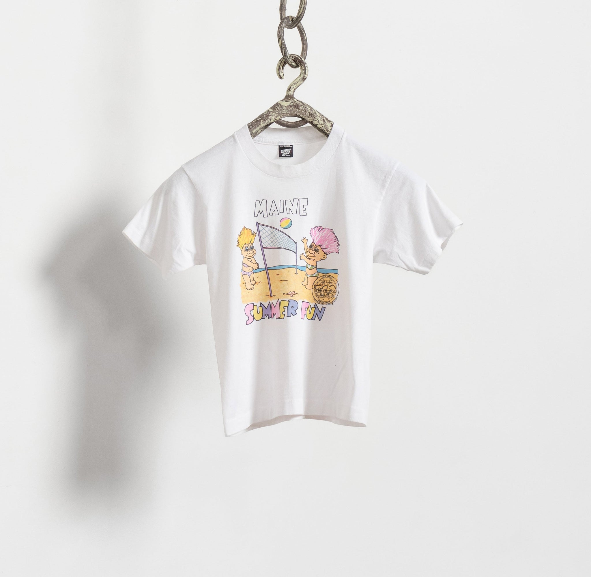 A white baby t-shirt with a vintage Maine Summer Fun troll print, hanging from a chain against a plain background.