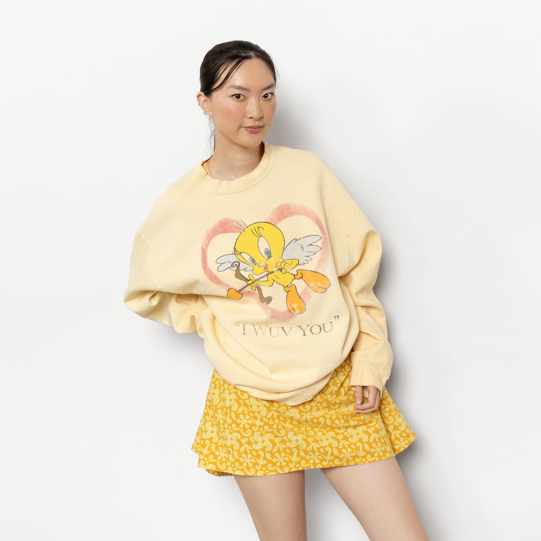 Person wearing a yellow sweater with a cartoon character and 'I love you' text, paired with a yellow skirt.