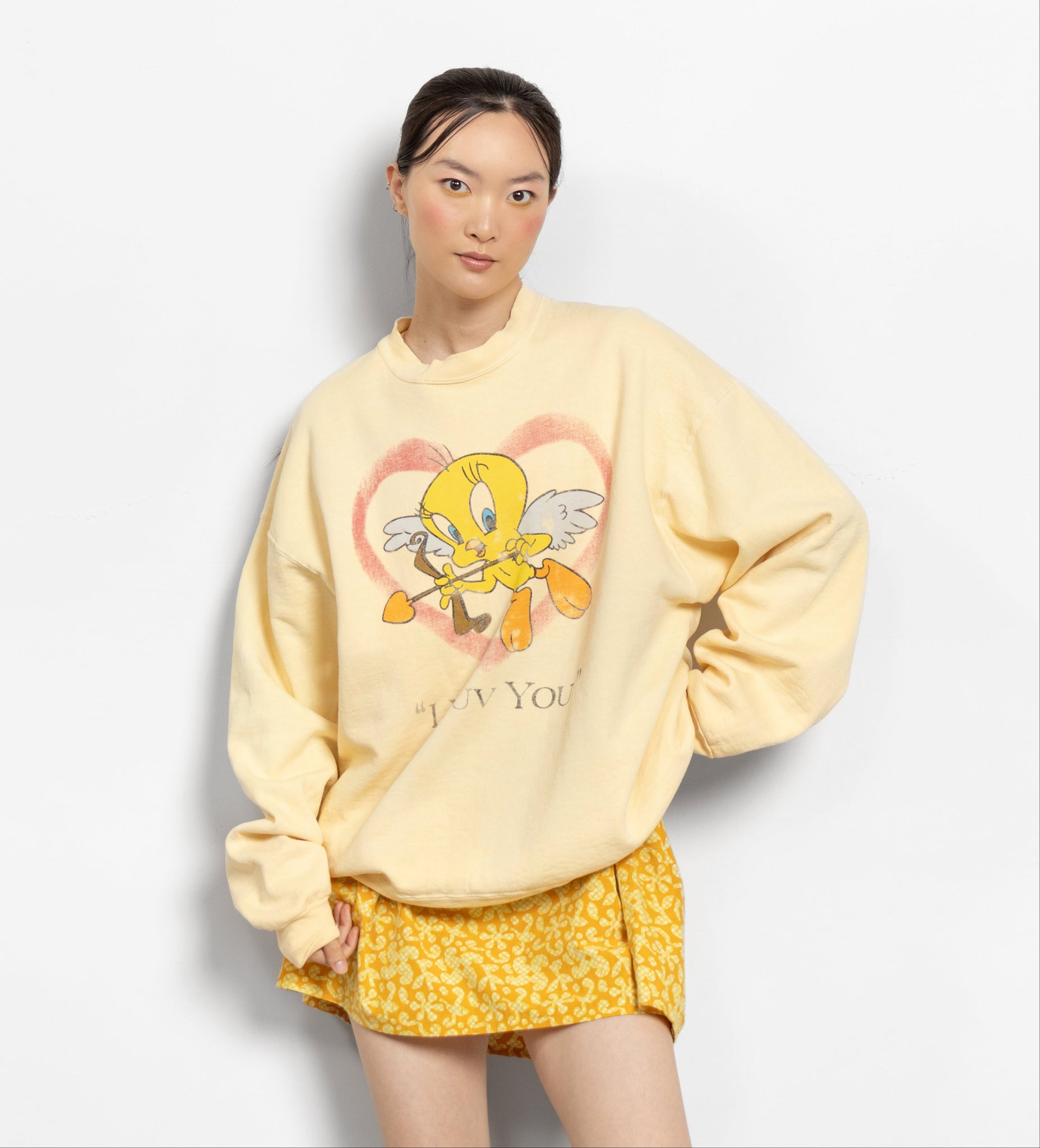 Person wearing a yellow sweatshirt with a cartoon character design on a white background