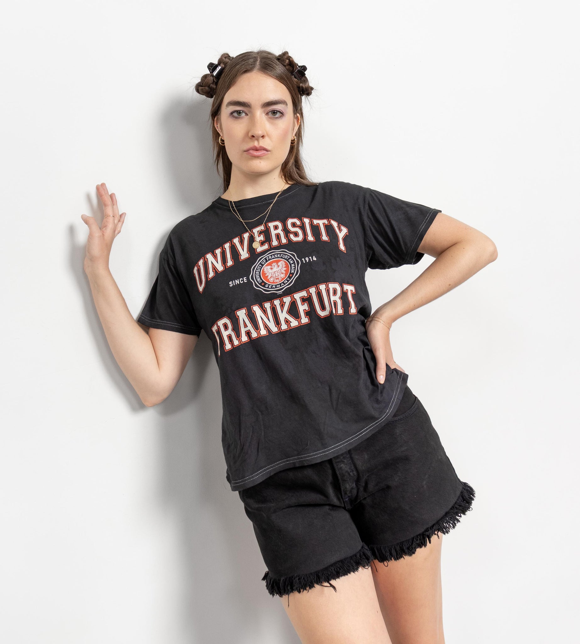 Person wearing a black 'University Frankfurt' t-shirt and shorts on a white background