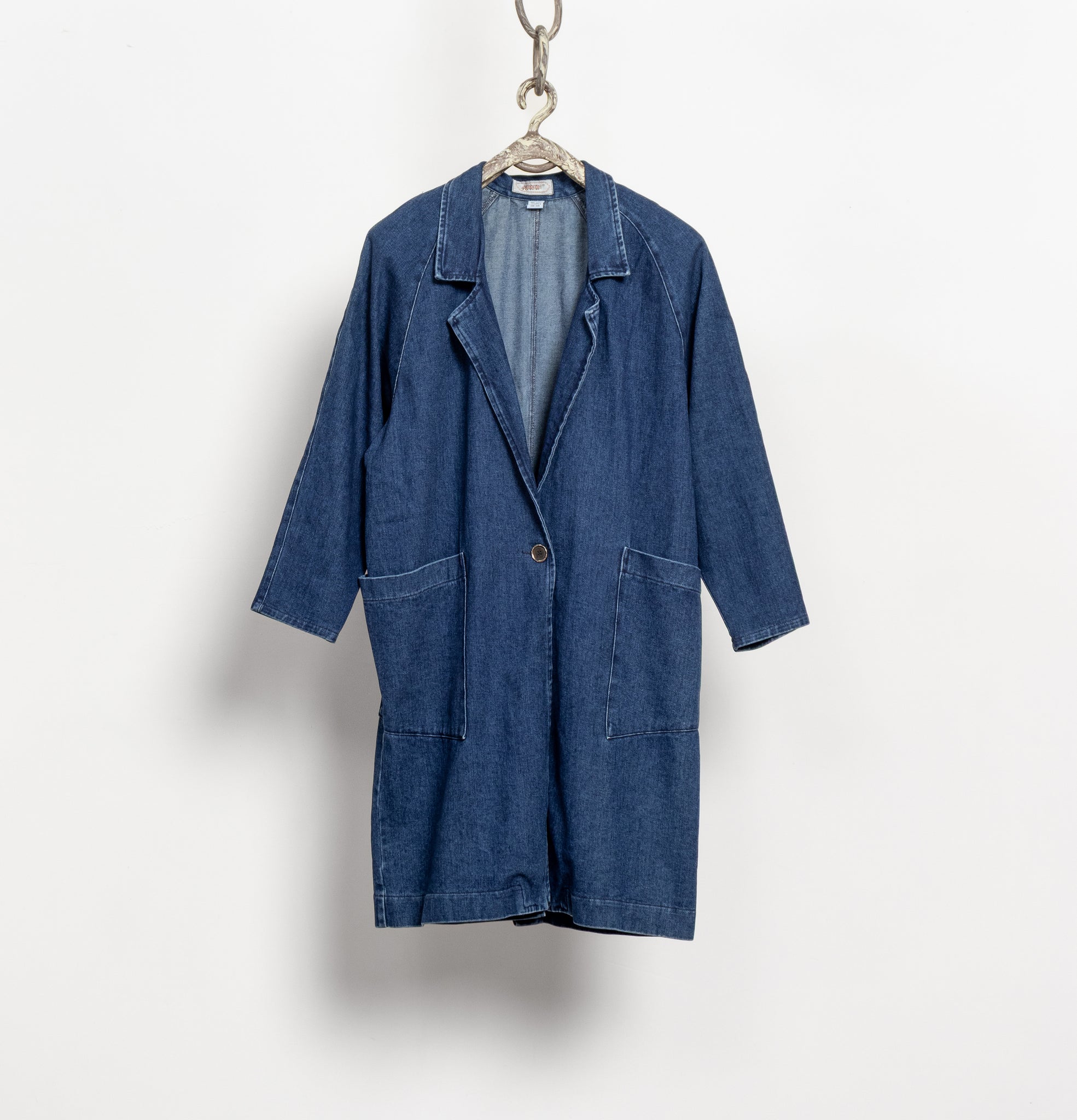 Blue denim coat on a hanger against a white background