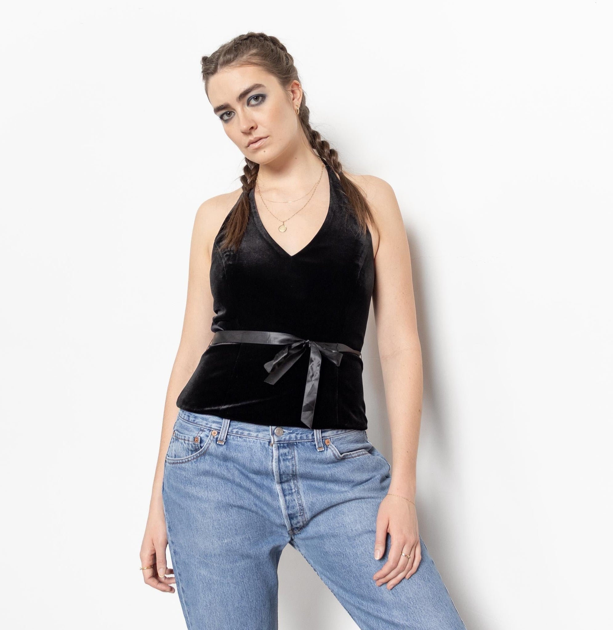 Woman wearing a black sleeveless top and blue jeans against a white background