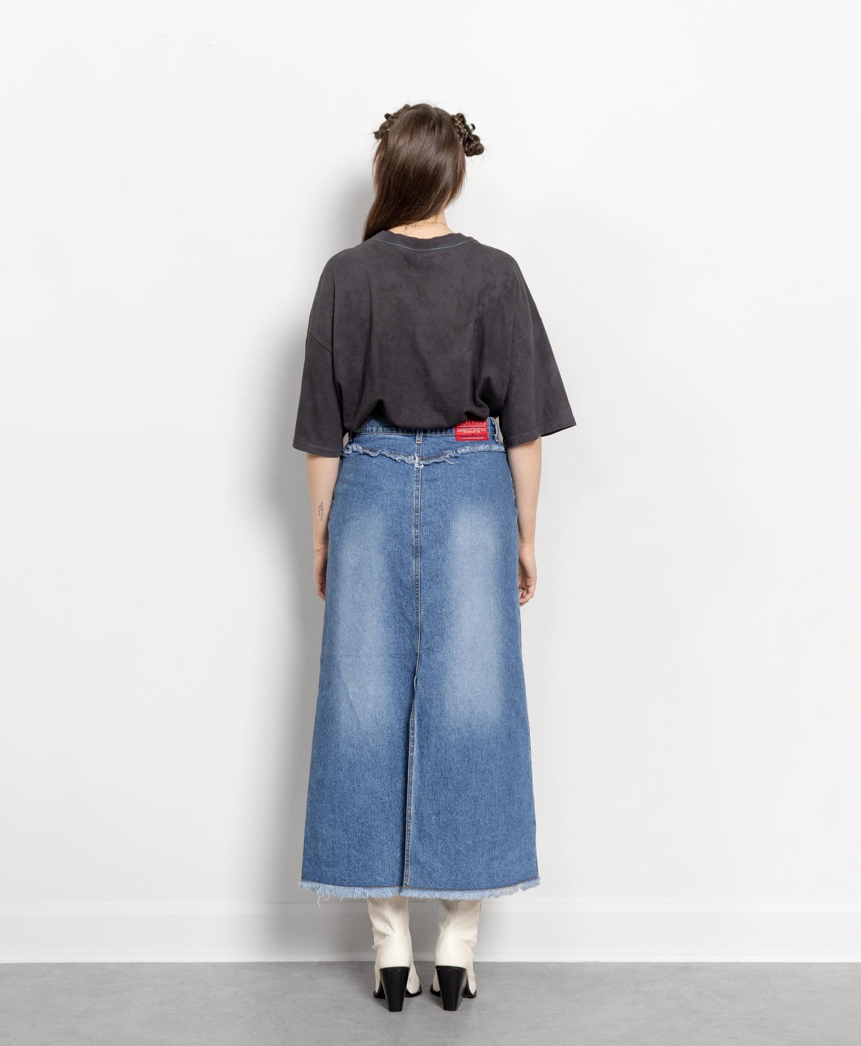 Person wearing a dark gray t-shirt and blue denim skirt on a white background