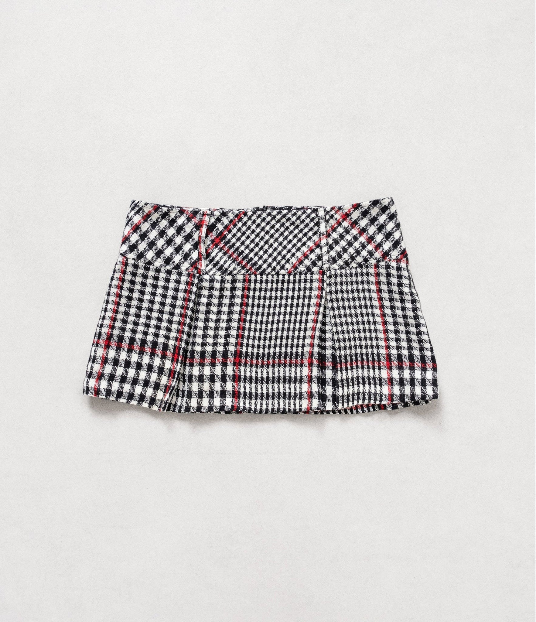 Plaid skirt with black, white, and red pattern on a light gray background