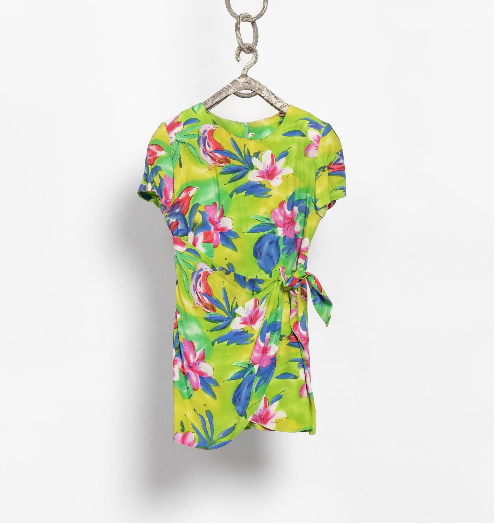 Colorful tropical print dress on a hanger against a white background