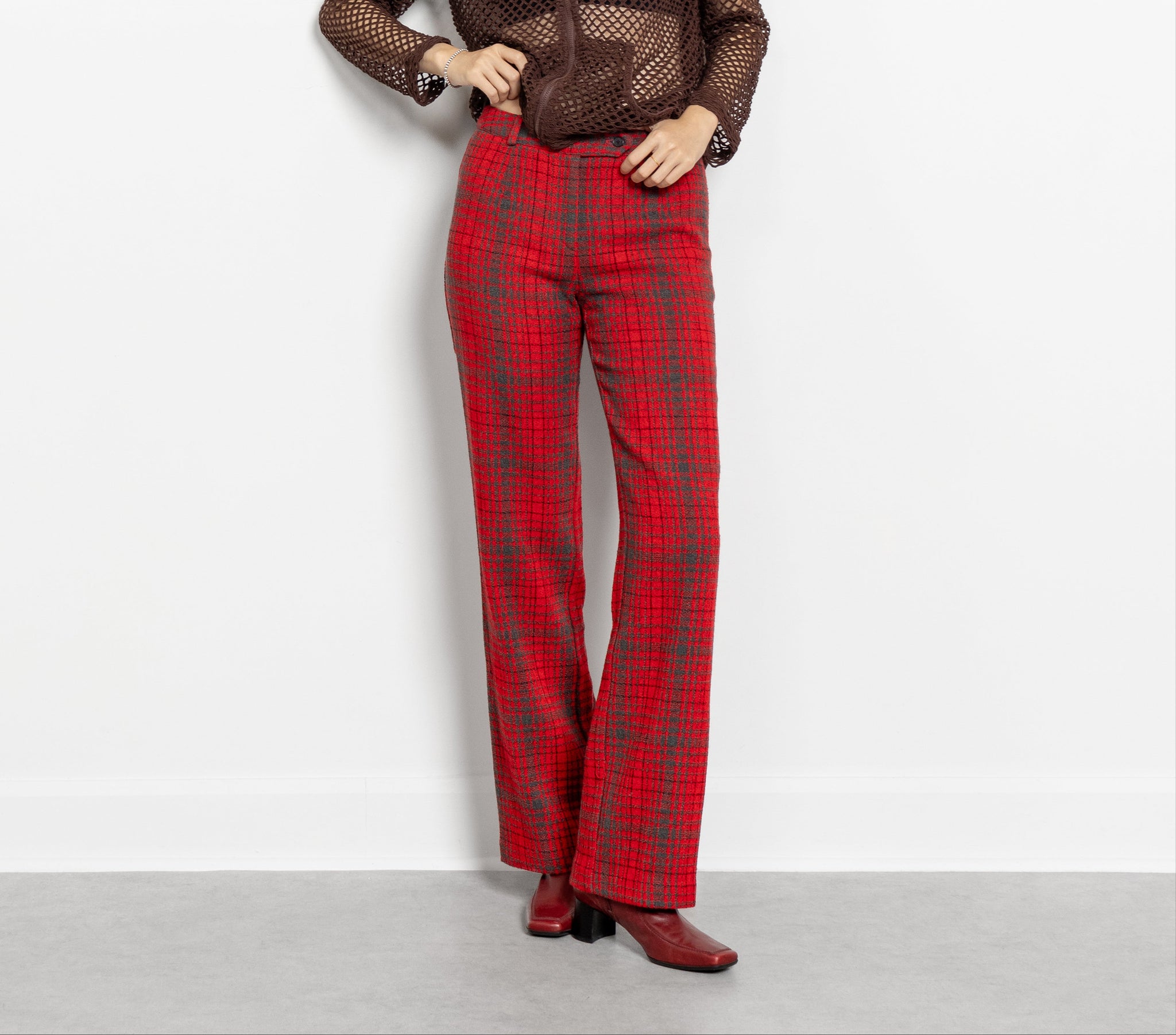 A person standing against a plain background, wearing red plaid wool-blend trousers with a low-rise waist and bootcut design.