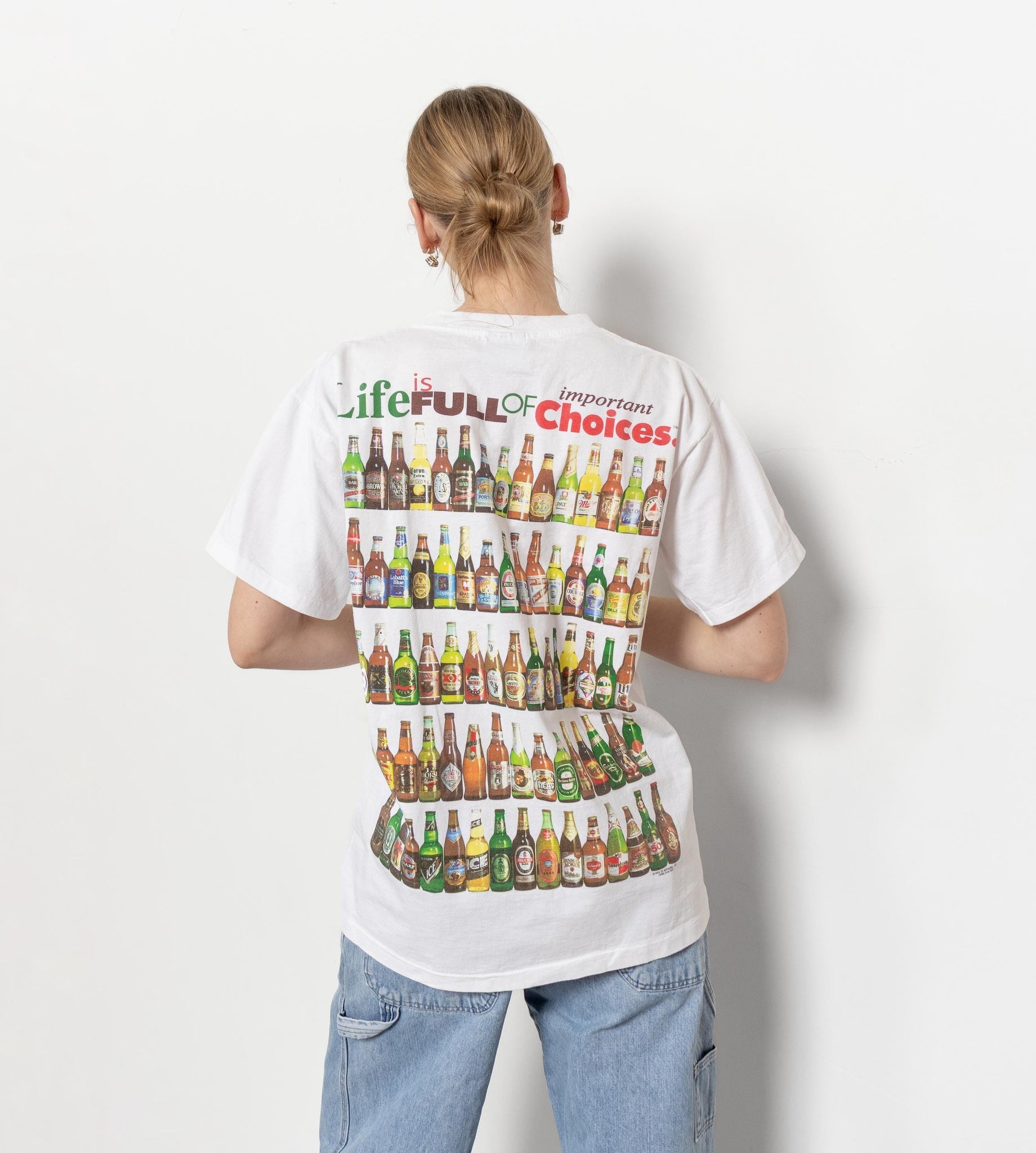 A person wearing a white short-sleeved t-shirt with a vintage beer print, facing away from the camera.