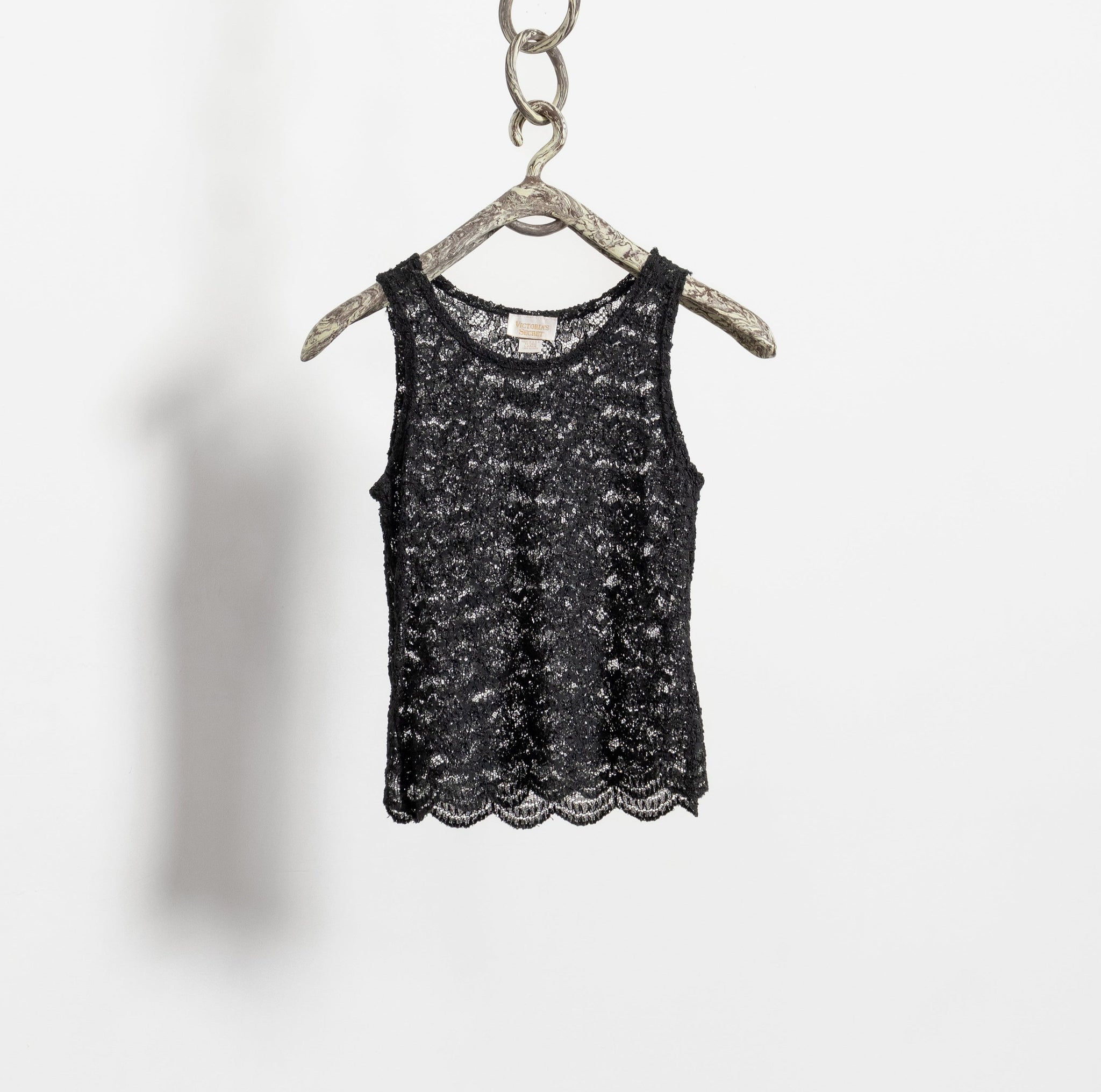Black tank top on a hanger against a white background