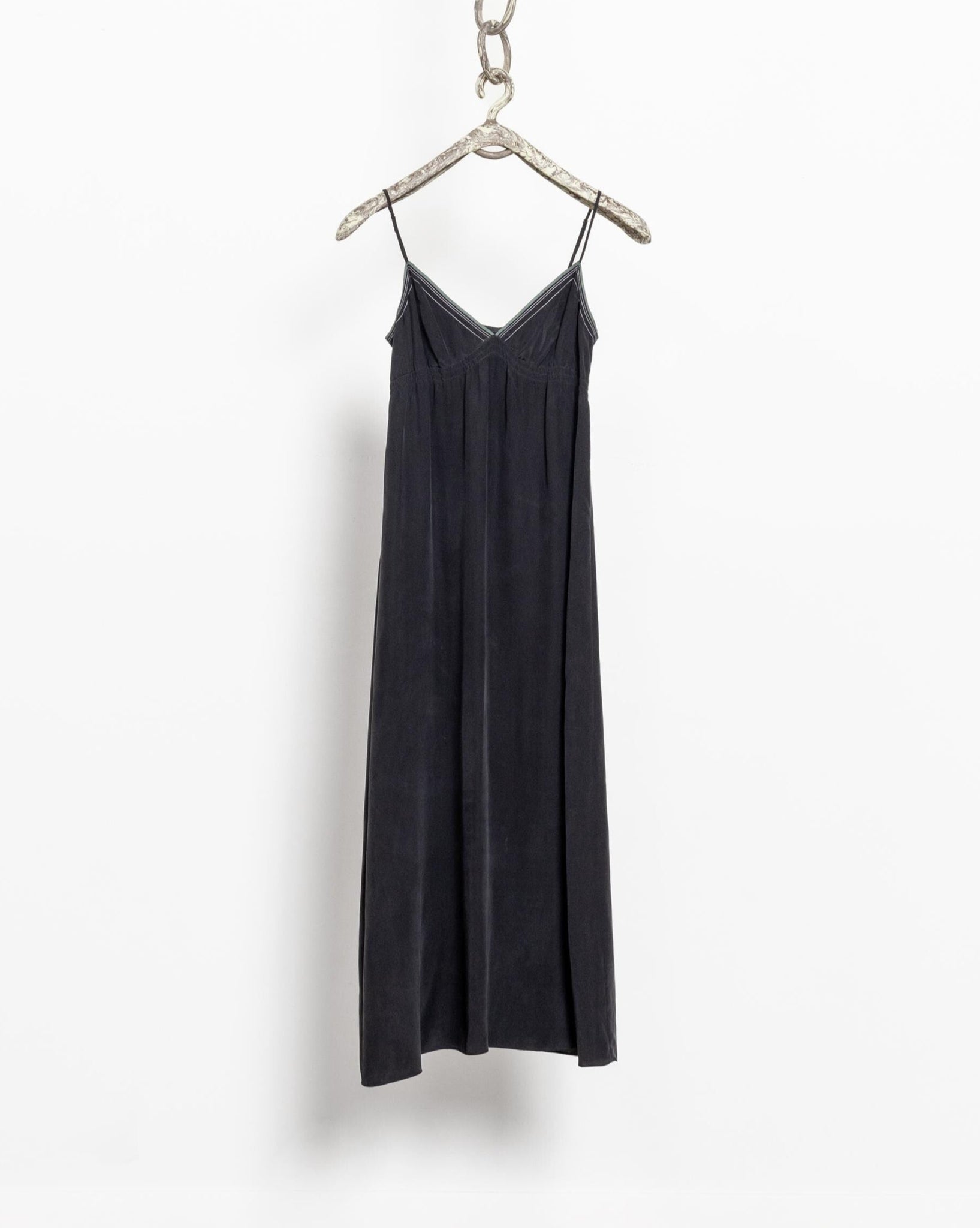 Black slip dress on a hanger against a white background
