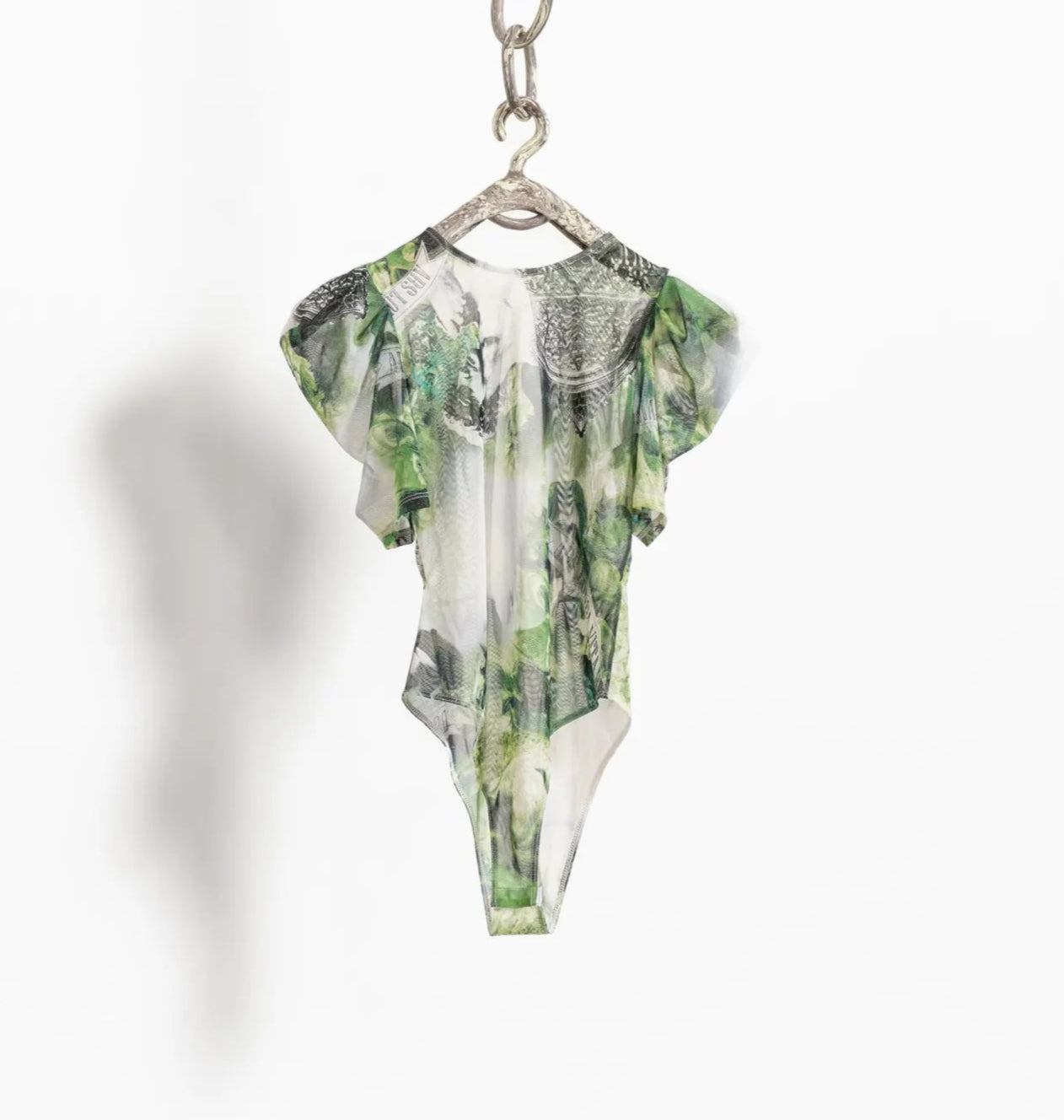 Green floral-patterned dress on a hanger against a white background