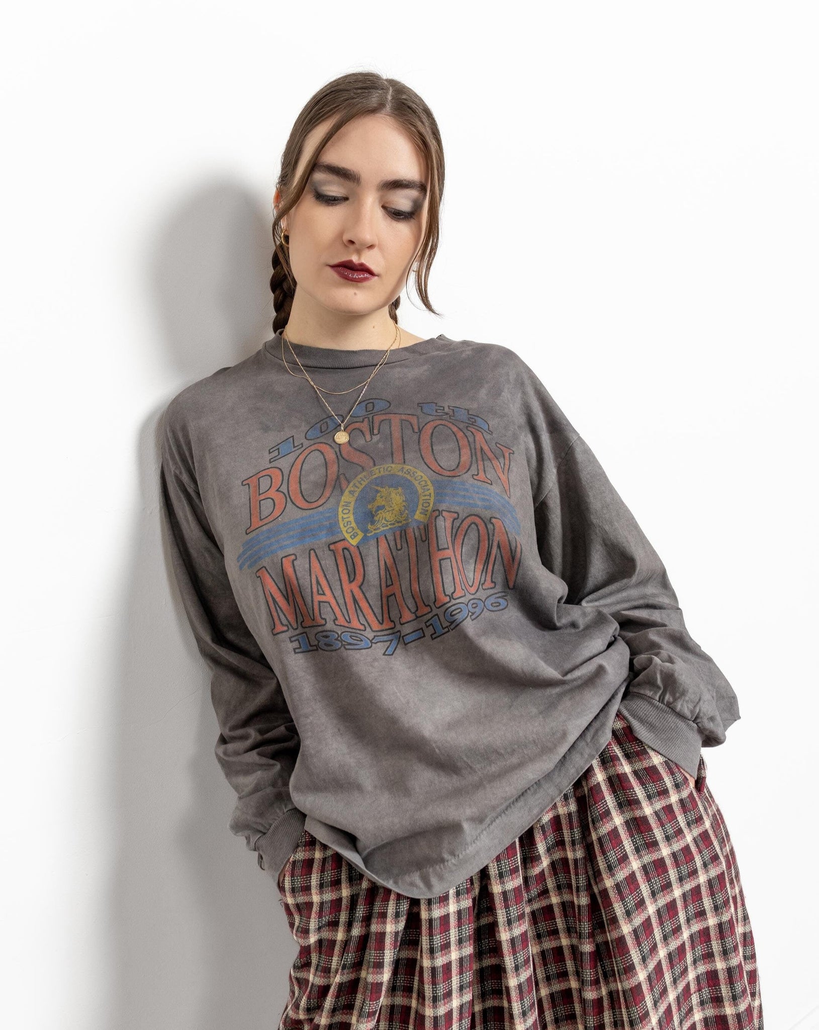 A person wearing a gray long-sleeve tie-dye Boston Marathon graphic t-shirt with the text 'Boston Marathon' printed in a larger font above a smaller font.