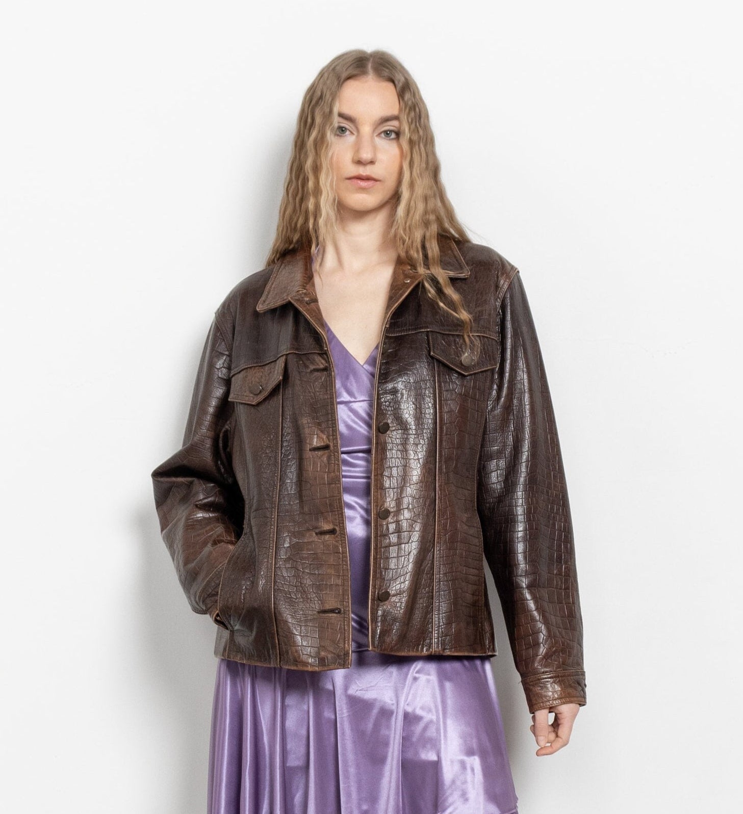 Person wearing a brown leather jacket over a purple dress on a white background