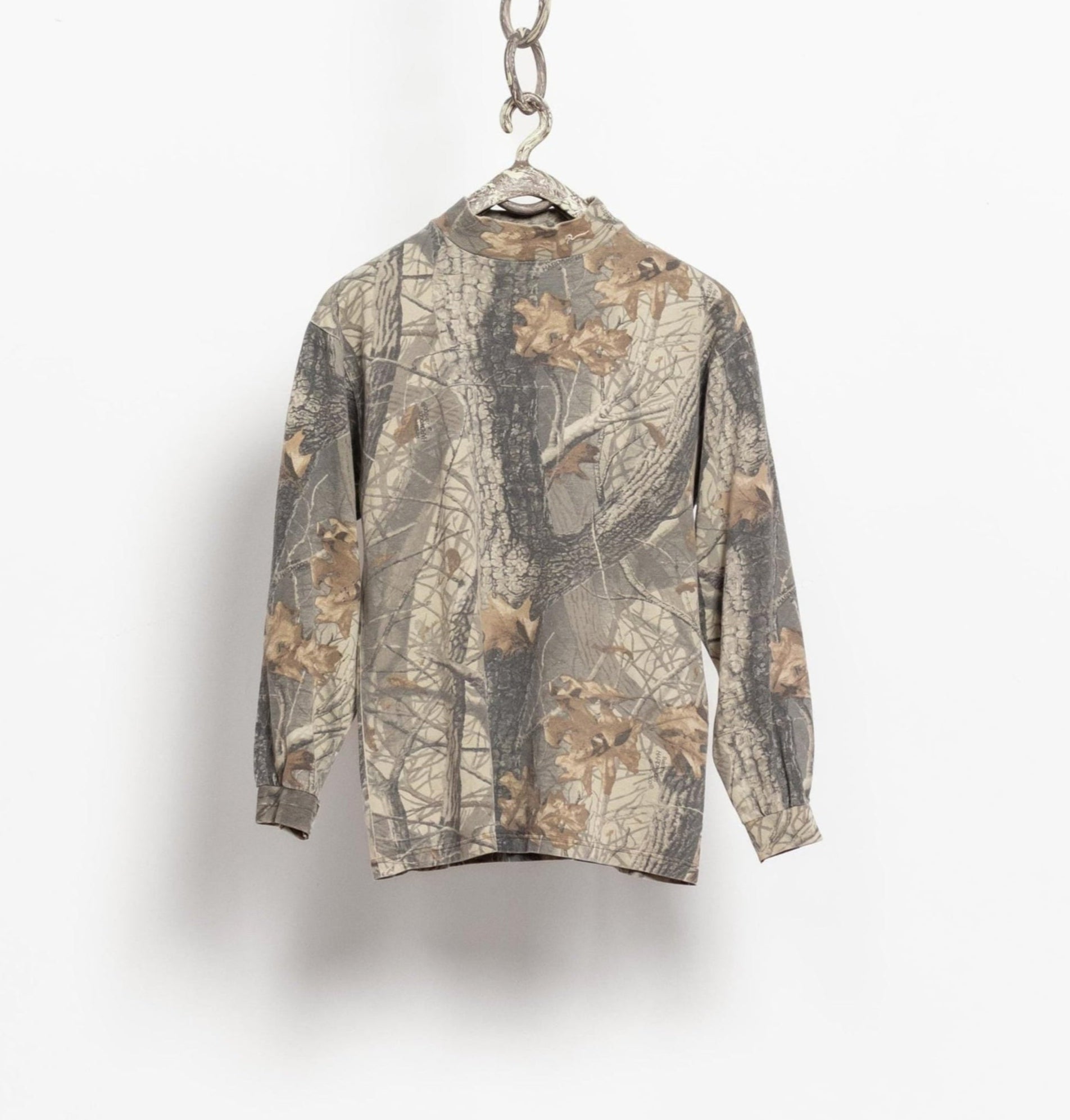 A long sleeve camouflage t-shirt hanging on a chain against a white background.
