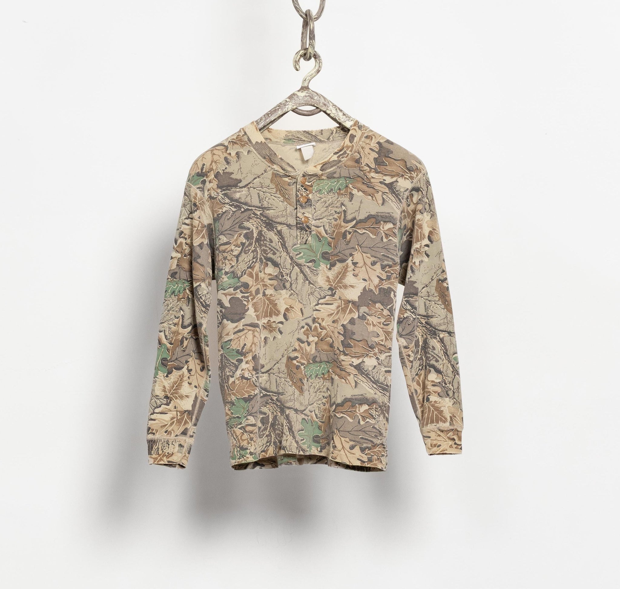 Camouflage long-sleeve shirt on a hanger against a white background