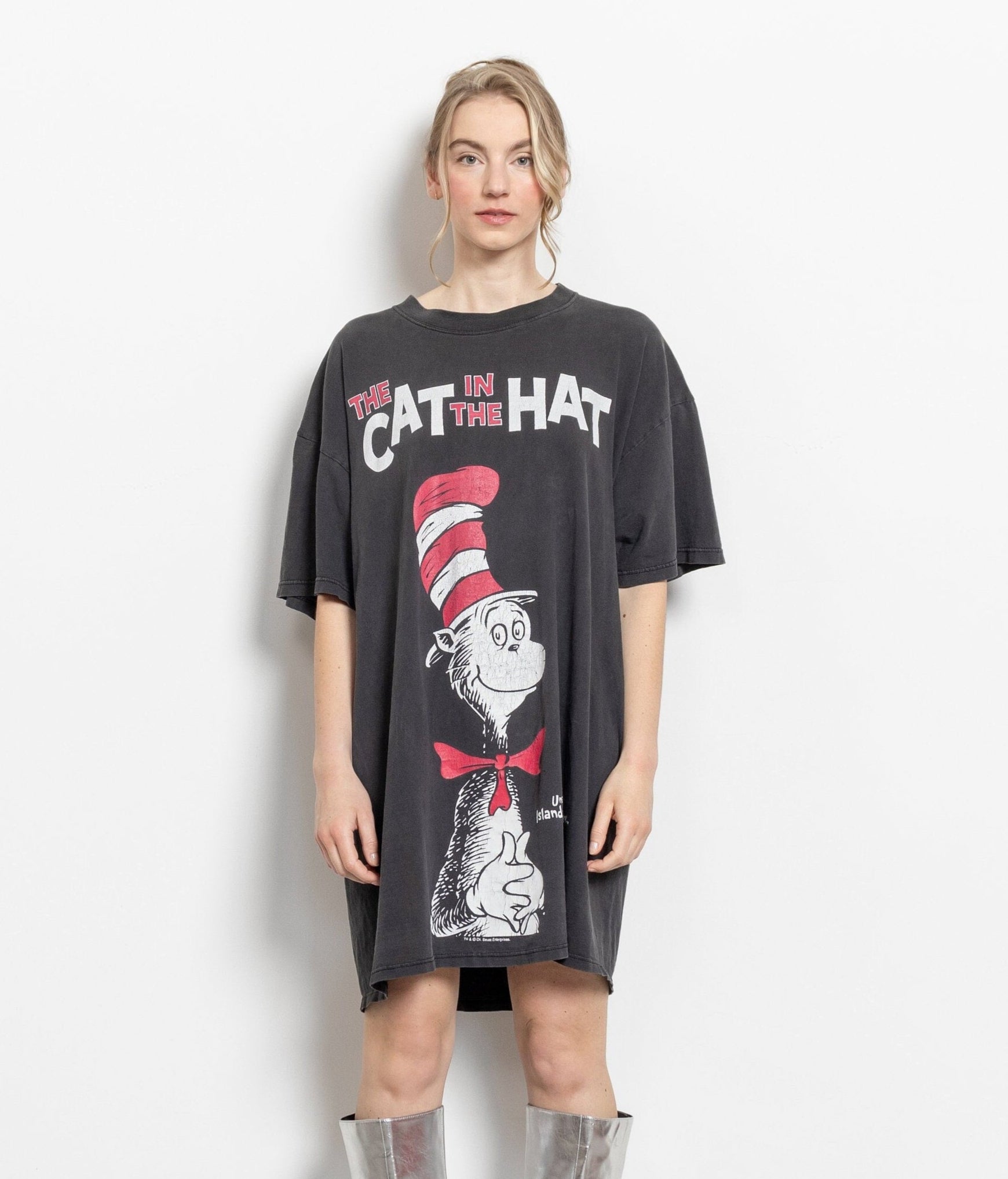 A woman modeling a long, oversized black t-shirt with a graphic print of 'The Cat In The Hat' from Dr. Seuss' books.