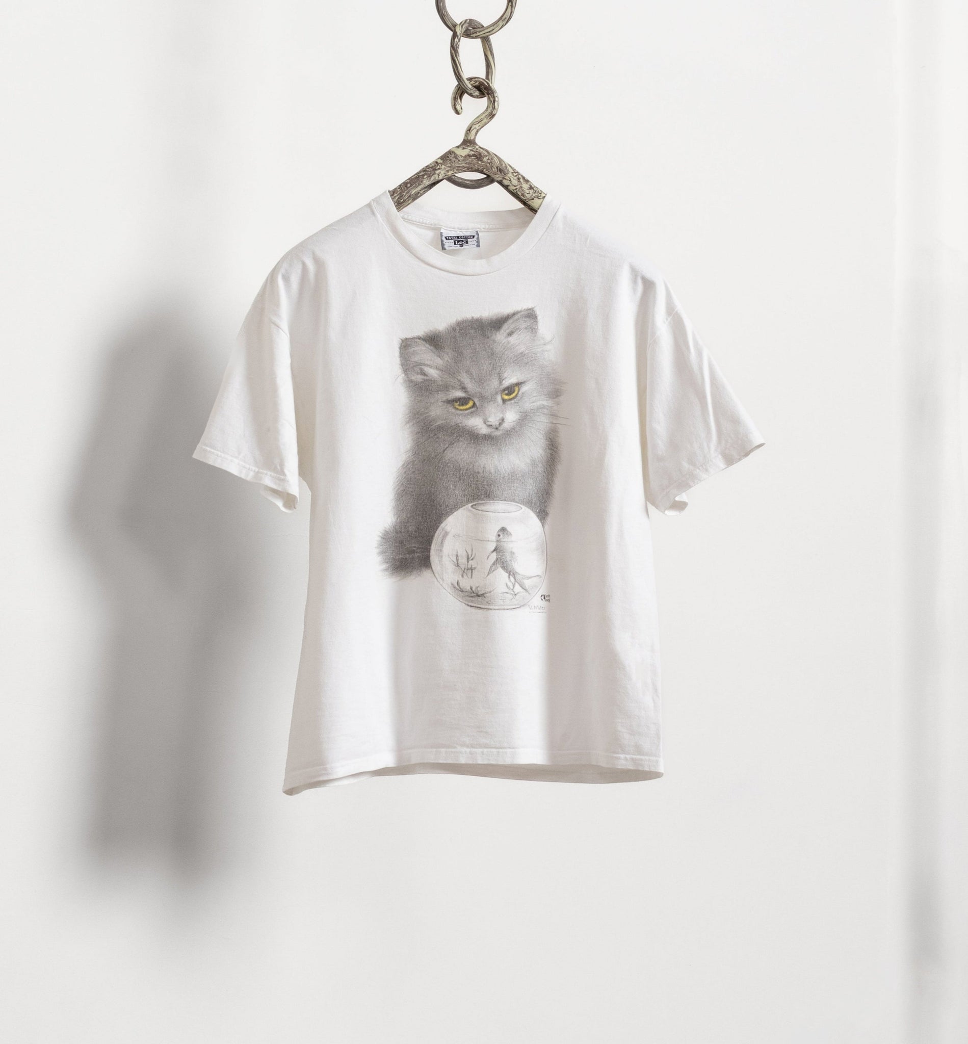 White t-shirt with a cat graphic on a hanger against a white background