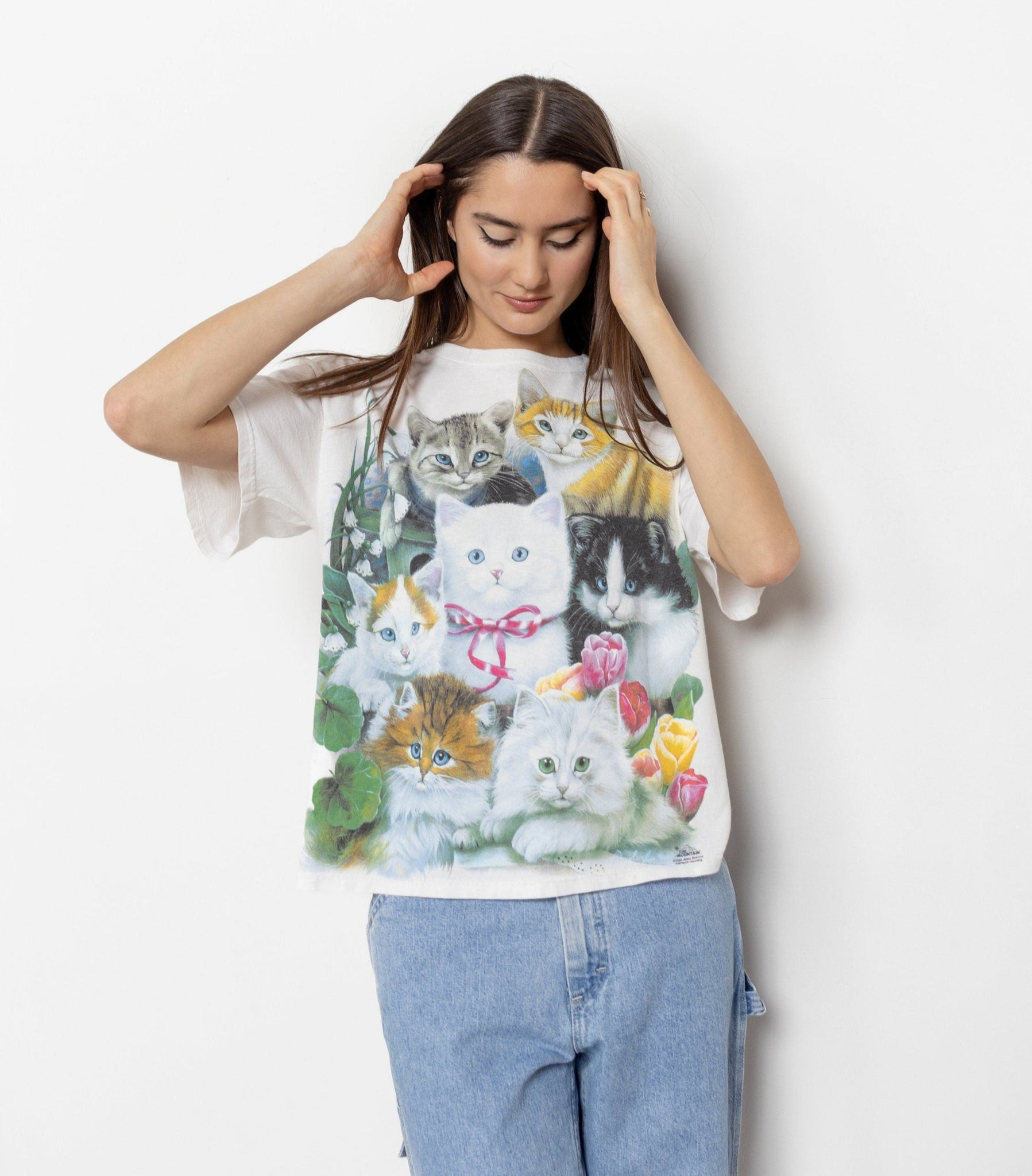 Woman wearing a t-shirt with a colorful cat print against a white background