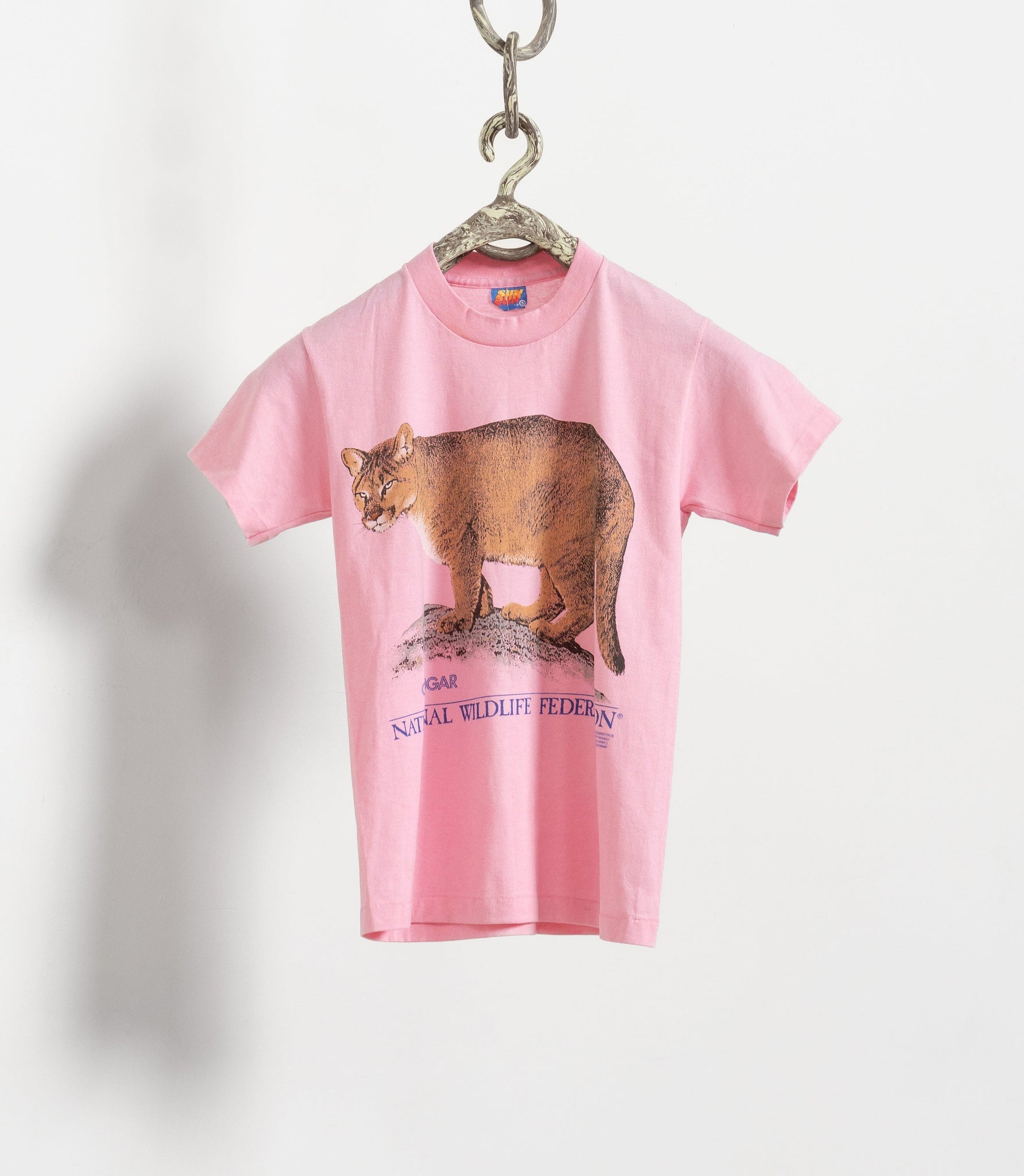 Vintage pink t-shirt with a cougar graphic, hanging on a hanger against a white background.