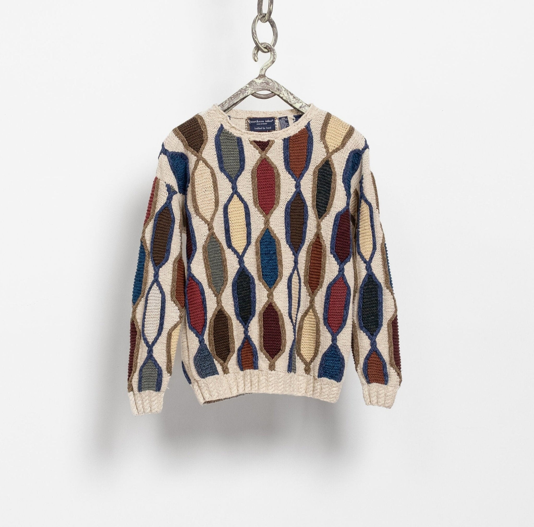 Patterned sweater on a hanger against a white background