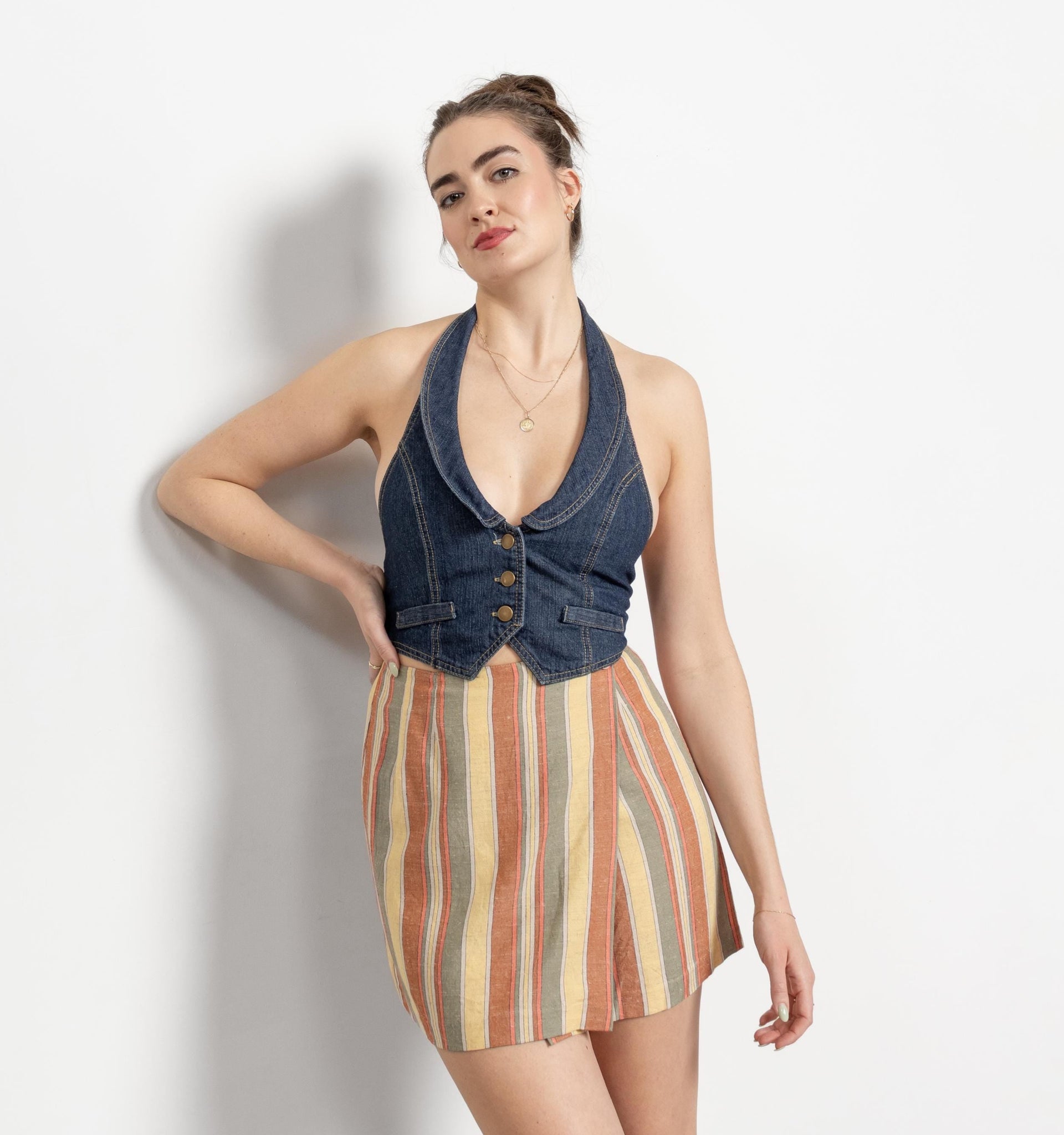 Woman wearing a denim halter top and striped skirt on a white background