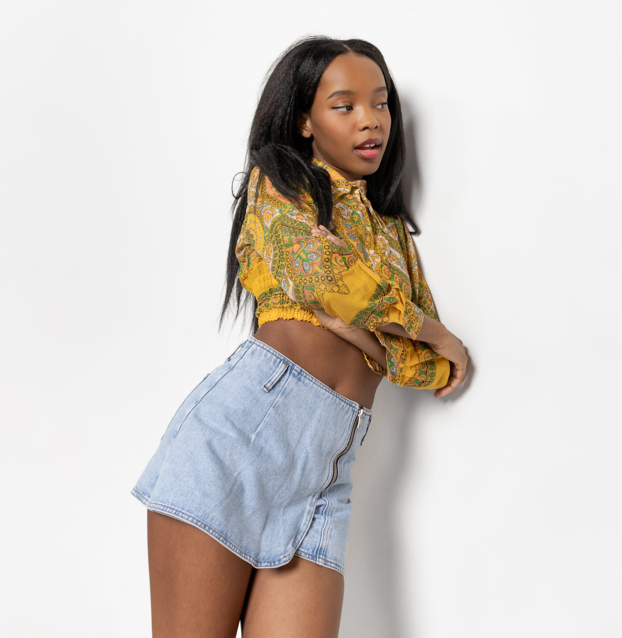 A person wearing a floral top and denim skort.