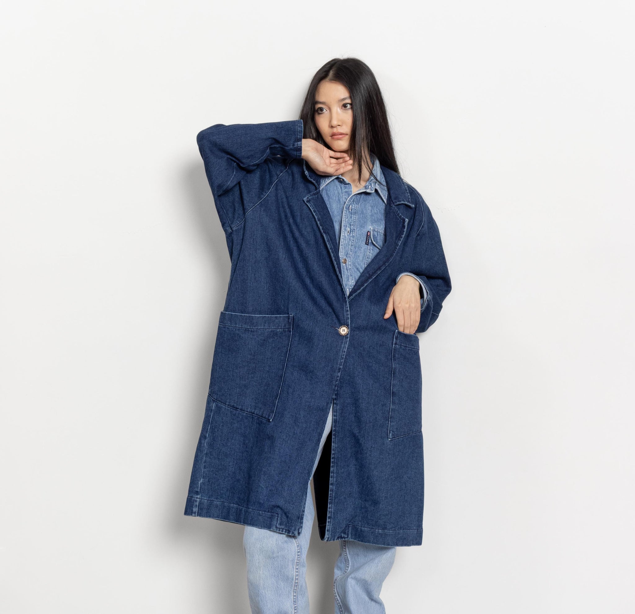 Person wearing a blue denim coat on a white background