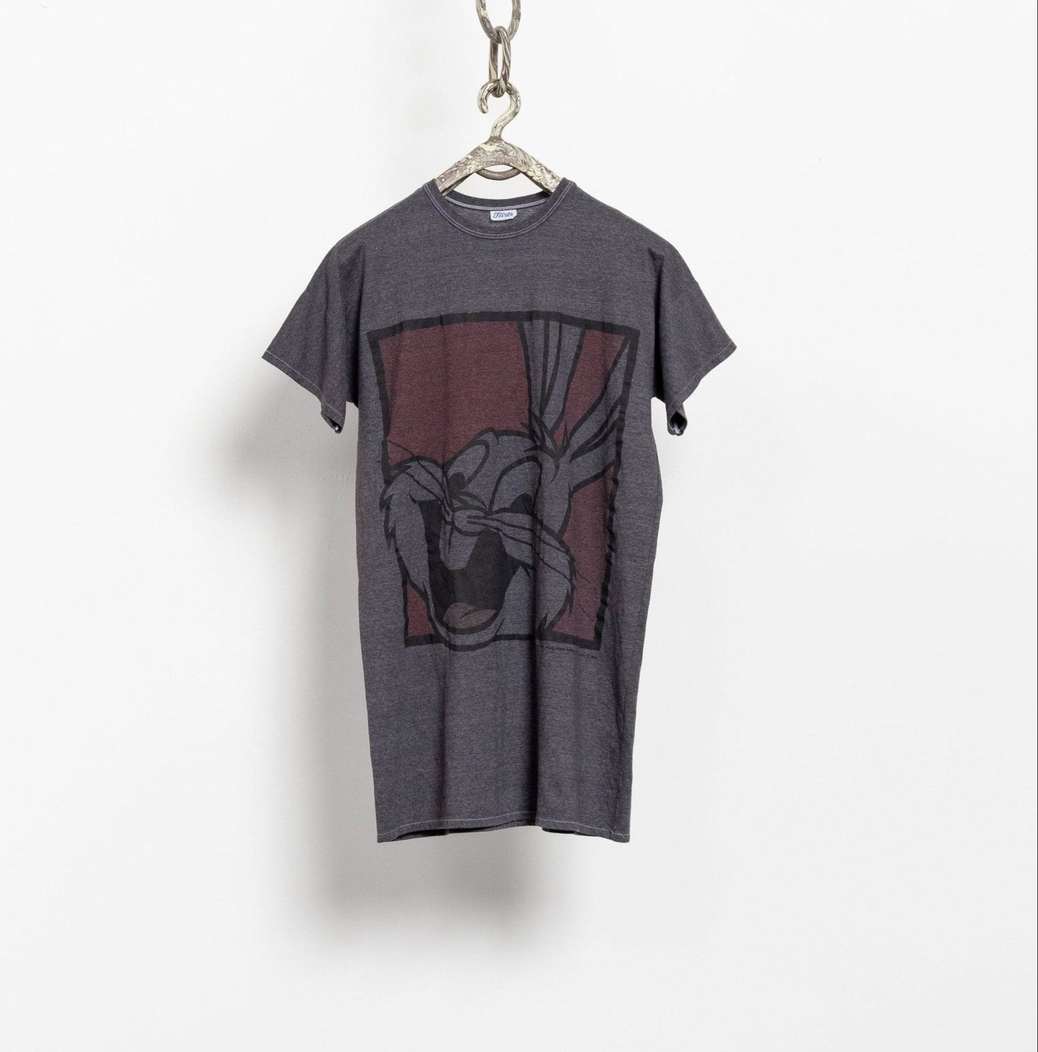 A vintage 90's style gray t-shirt with a crew-neckline and short sleeves, featuring a large graphic print of Bugs Bunny in the center, with a chain hanging from the neck.