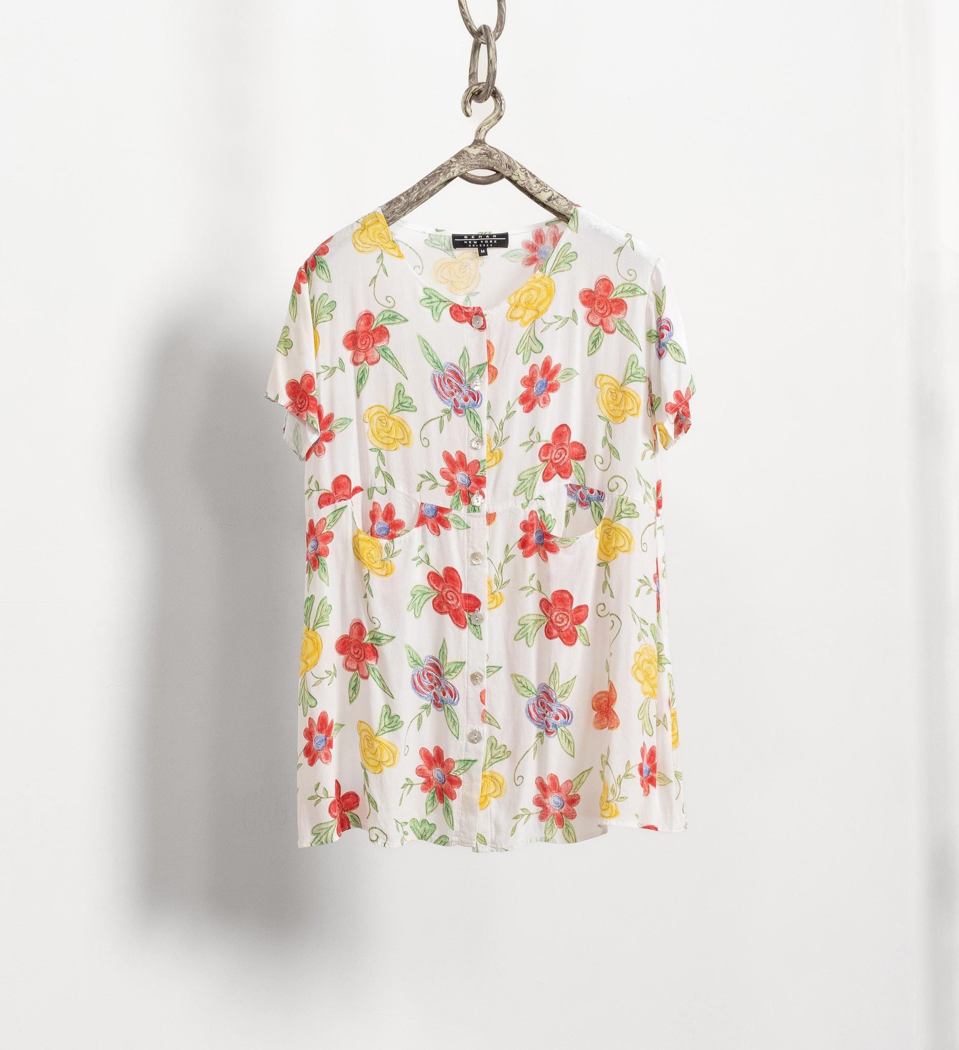 Floral-patterned shirt on a hanger against a white background