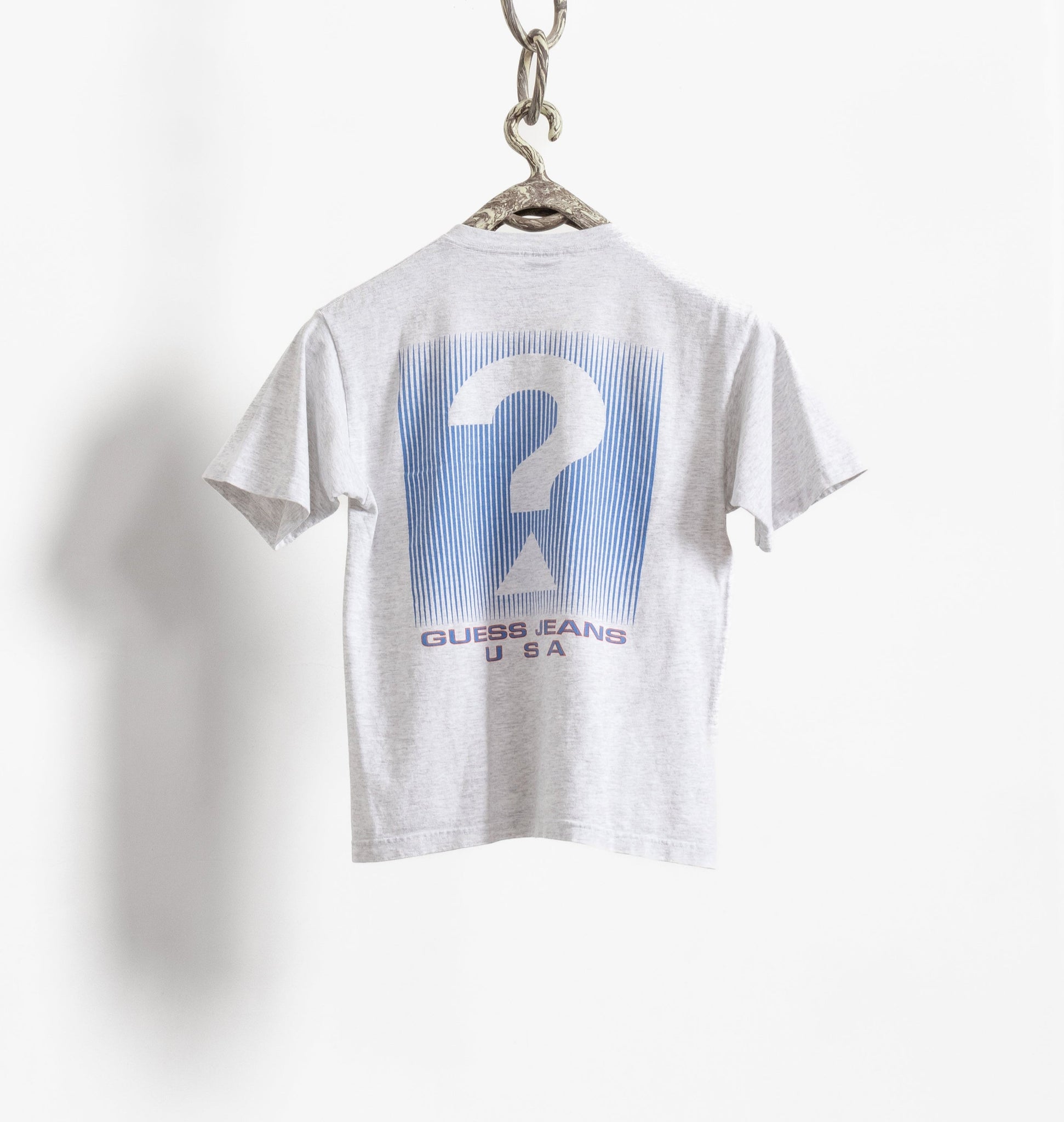 A heather grey Guess Jeans t-shirt with a large graphic on the back, featuring a question mark design, displayed on a white background.