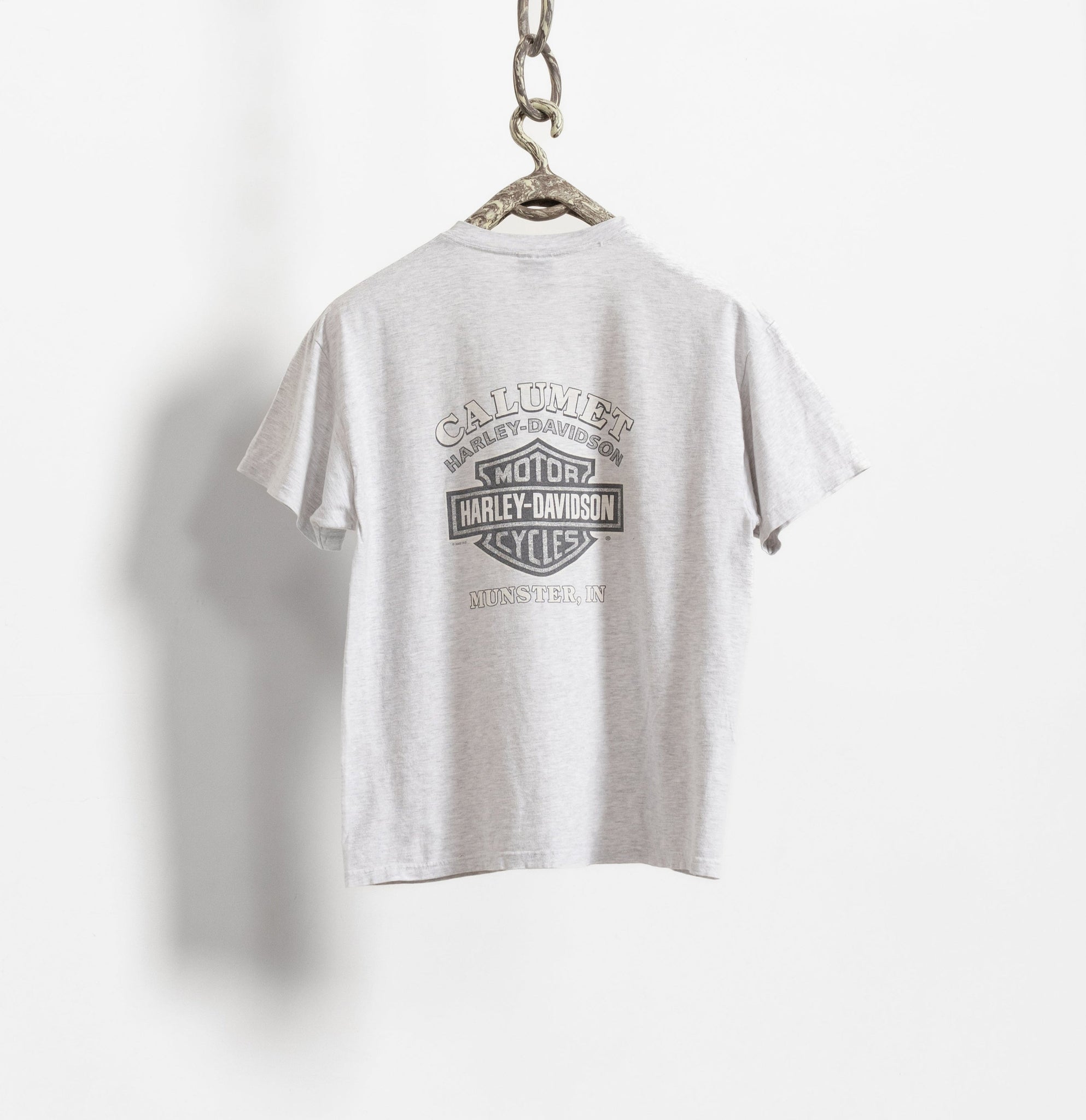 A white Harley Davidson graphic t-shirt hanging on a display chain against a white background.