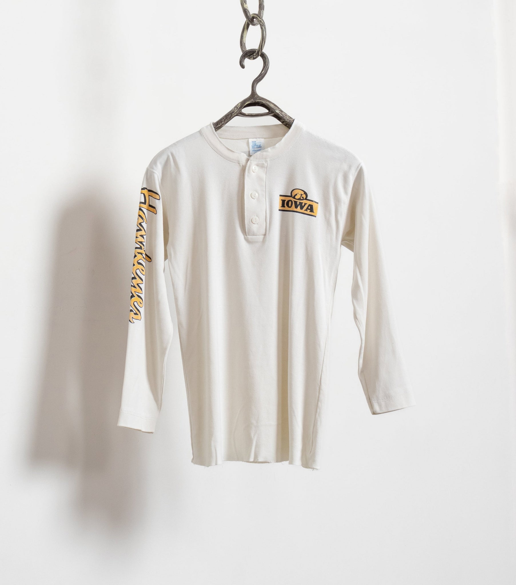 White long-sleeve shirt with a logo on a hanger against a white background