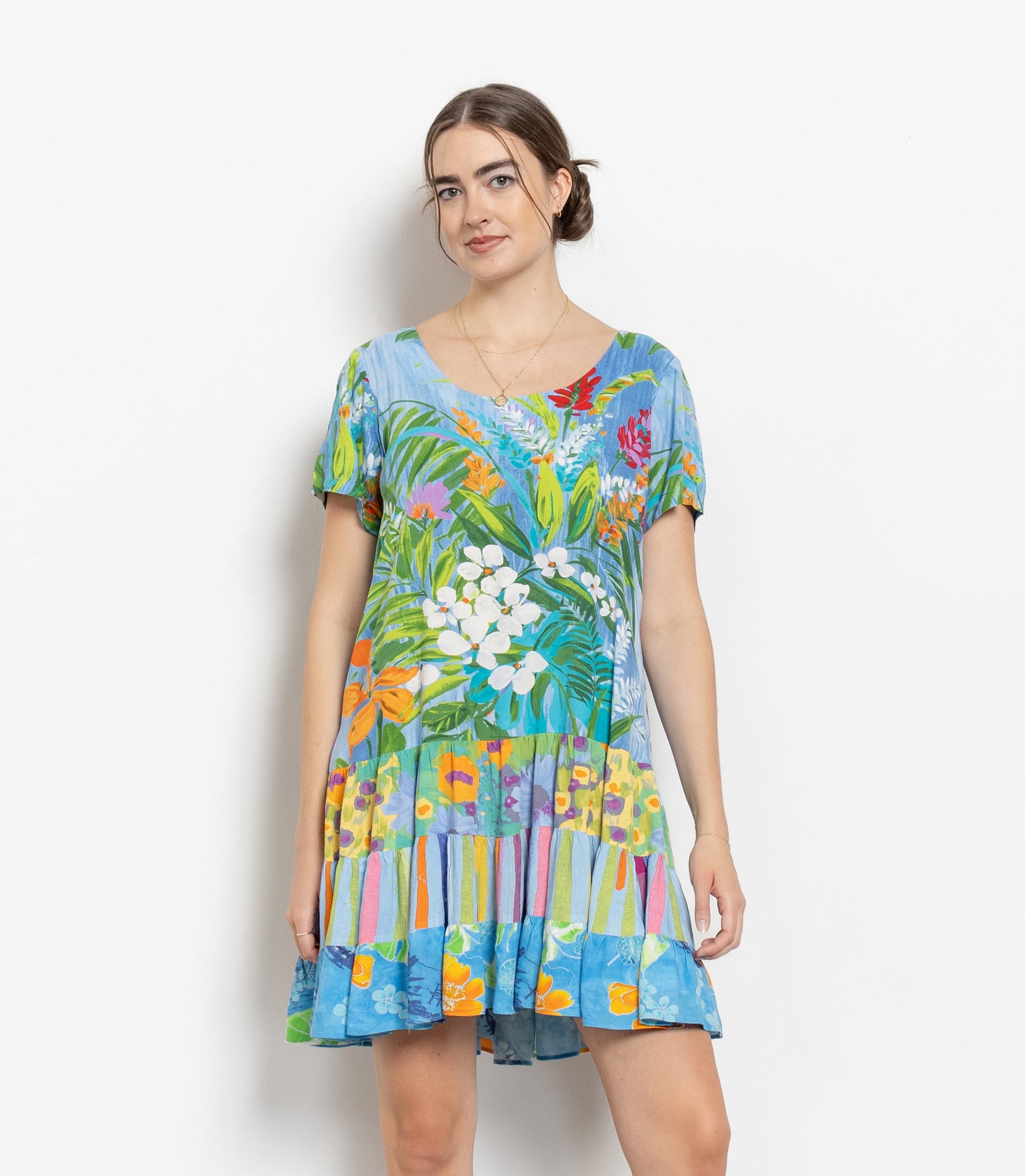 A woman modeling a vintage 90's floral short sleeve flowy mini dress with a Cascade of ruffles