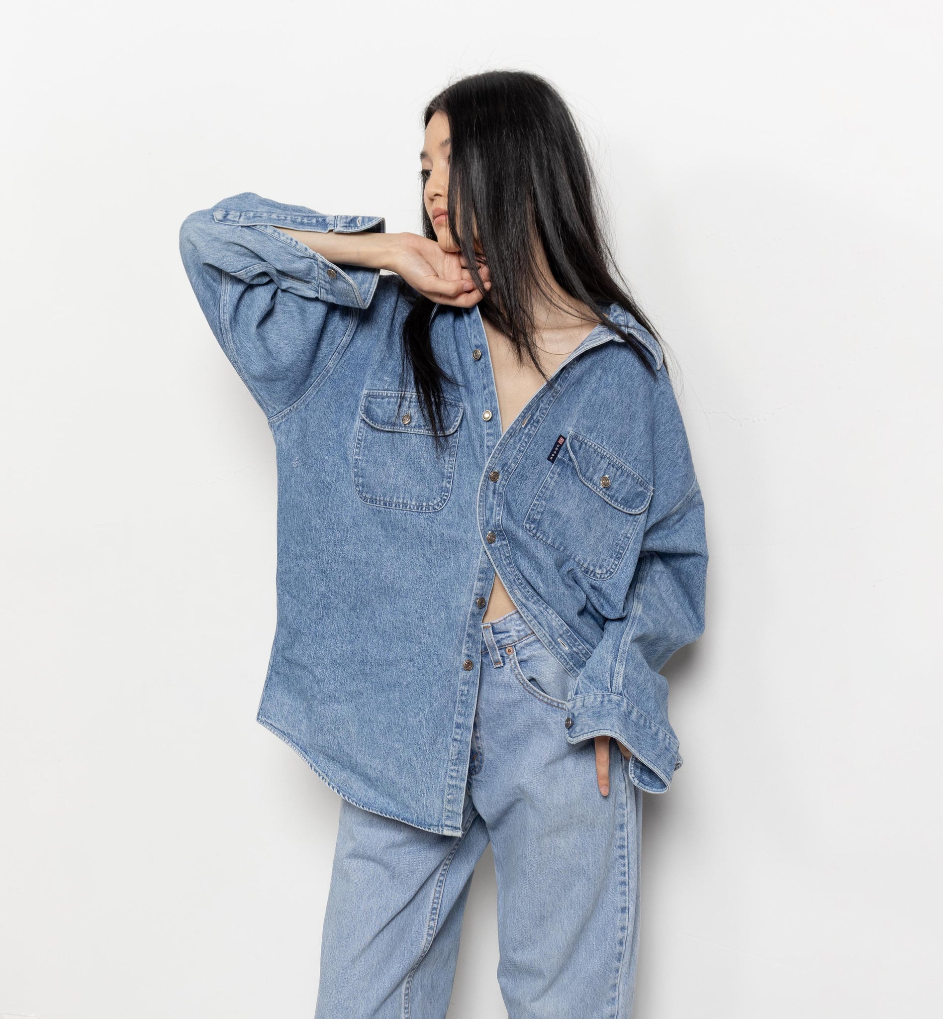 Person wearing a light blue denim outfit against a white background