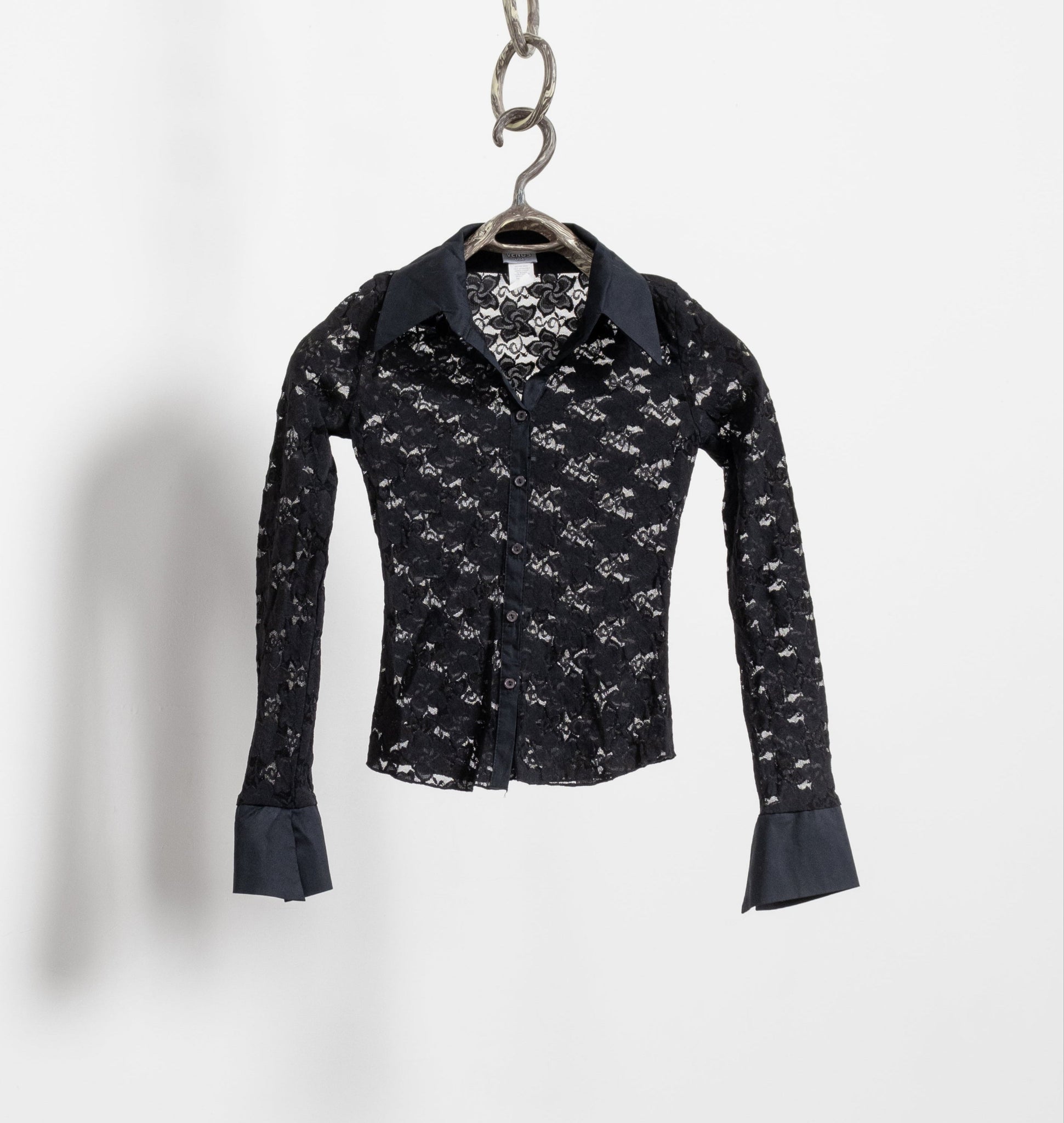 Black patterned shirt hanging on a silver hook against a white background