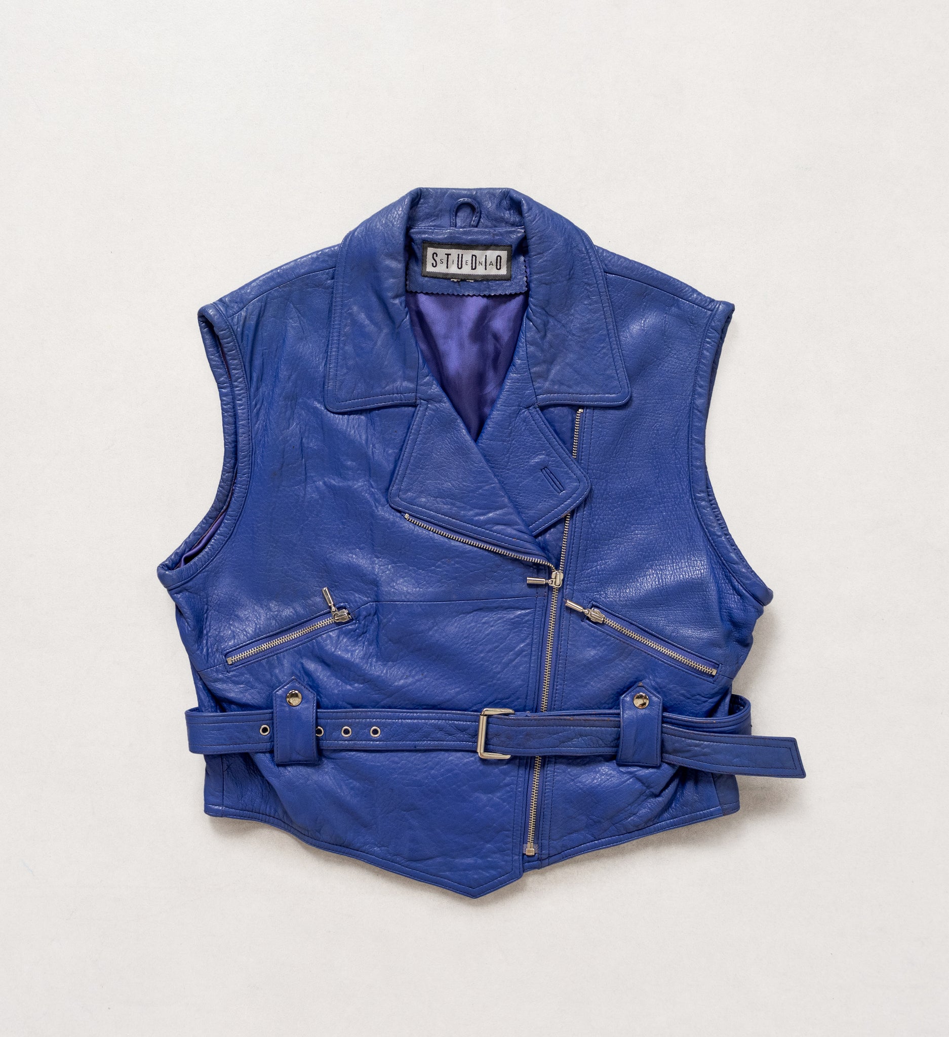 Blue leather vest with zippers on a light gray background