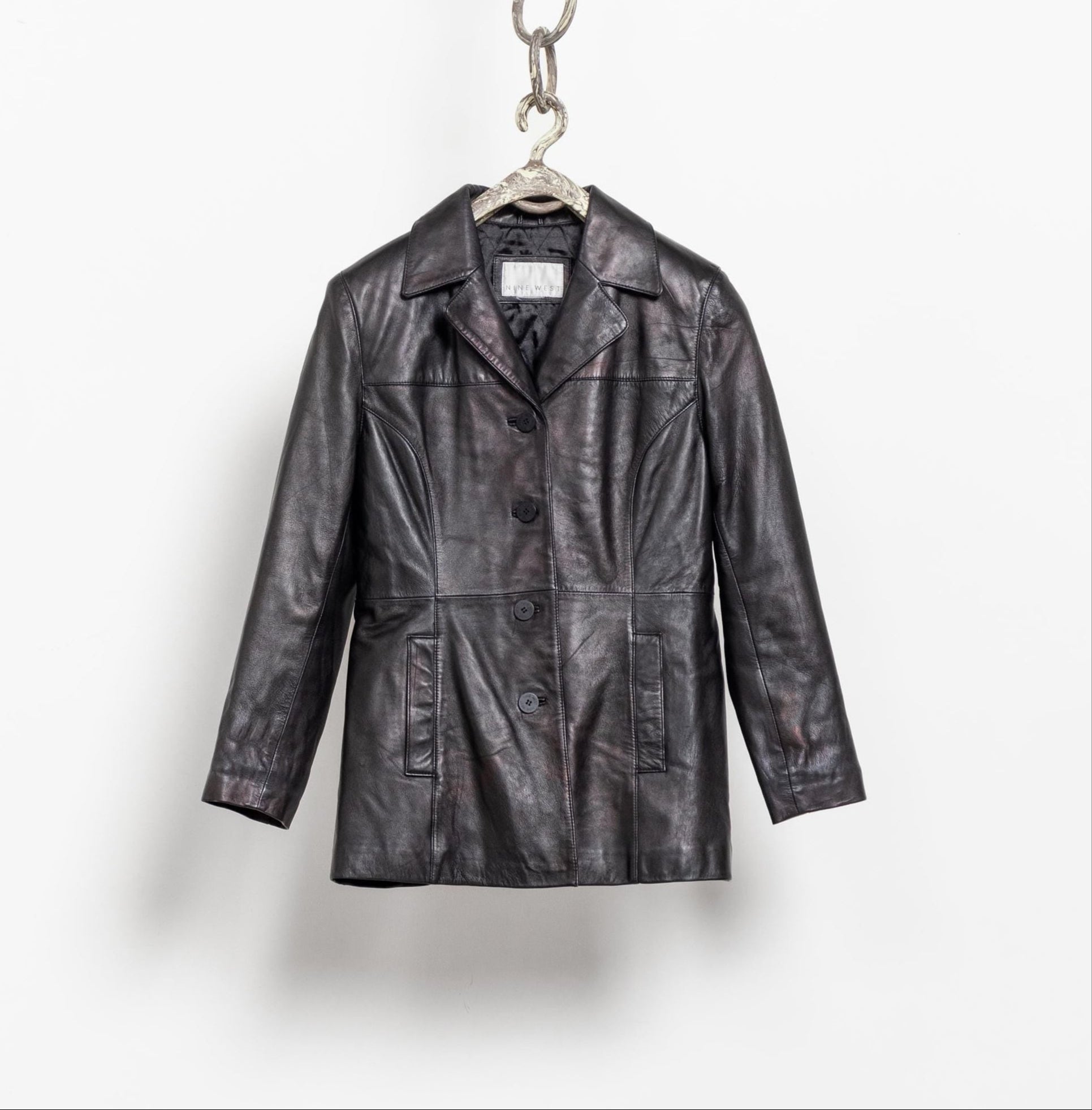 Black leather jacket on a hanger against a white background
