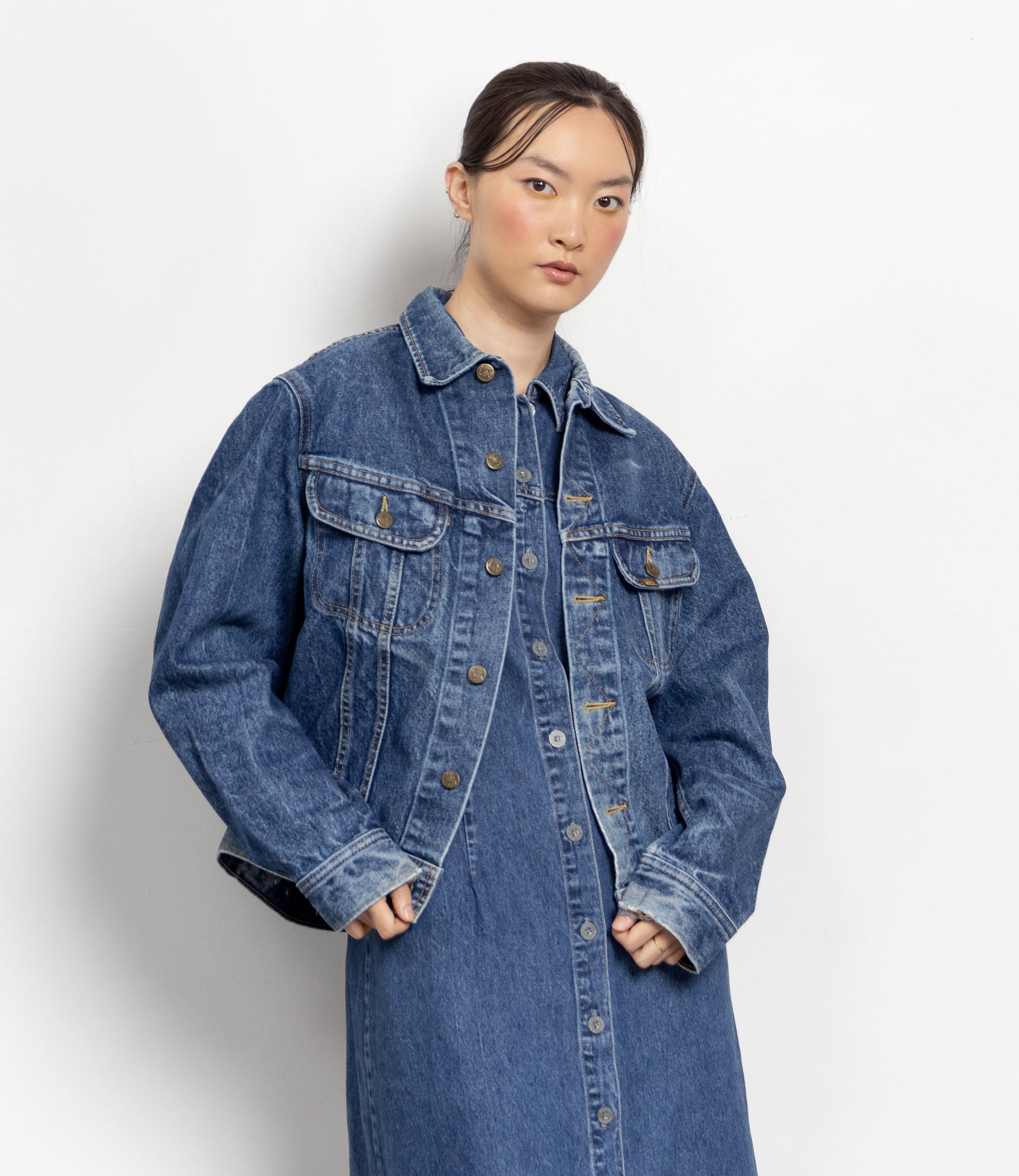 Person wearing a long denim jacket on a white background