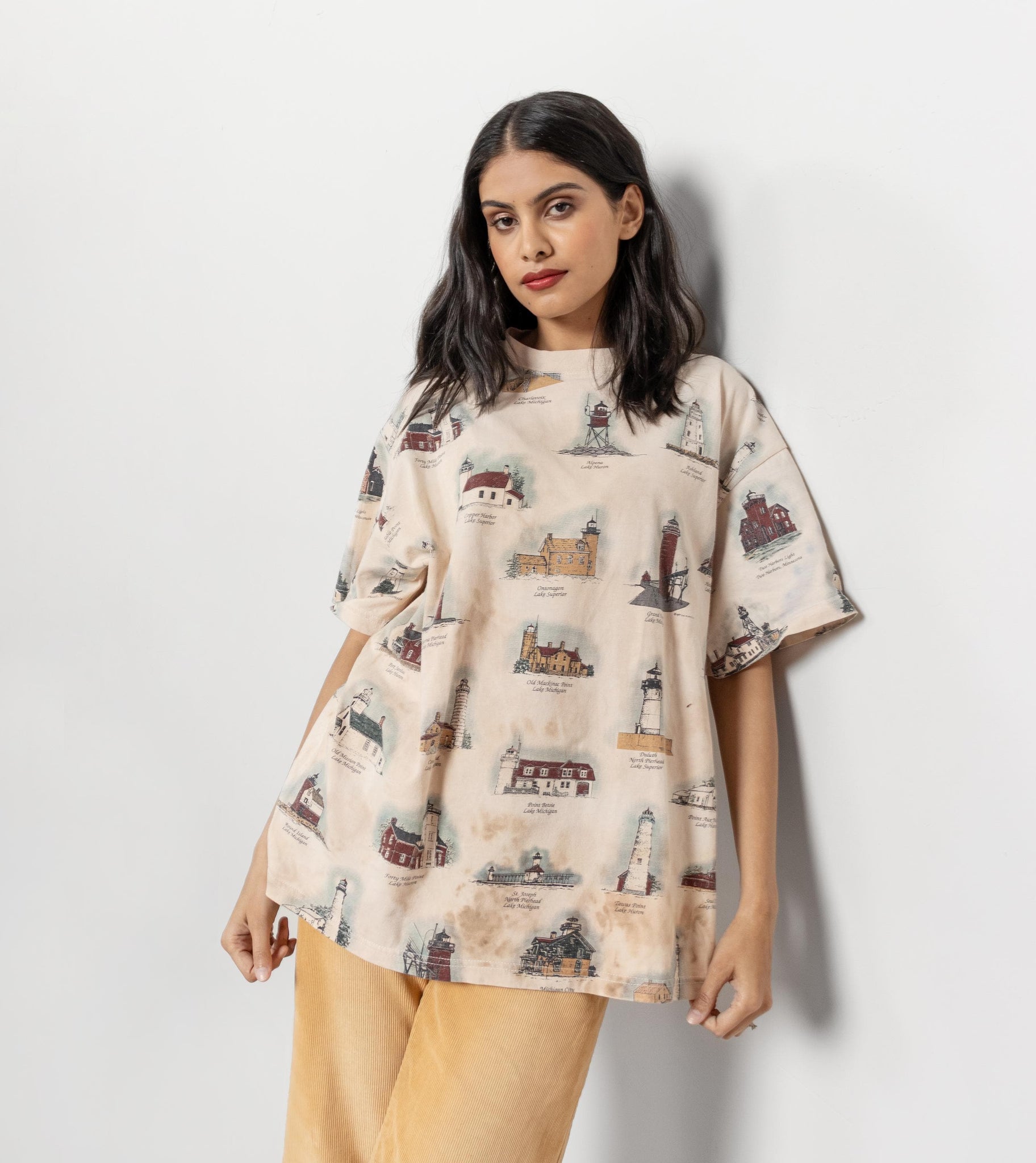 Woman wearing a beige t-shirt with a lighthouse pattern against a white background