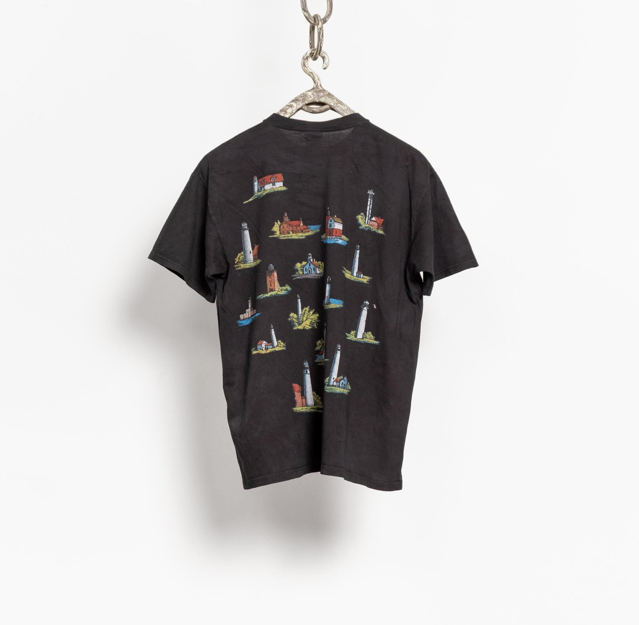 Black t-shirt with colorful lighthouse design on a hanger against a white background
