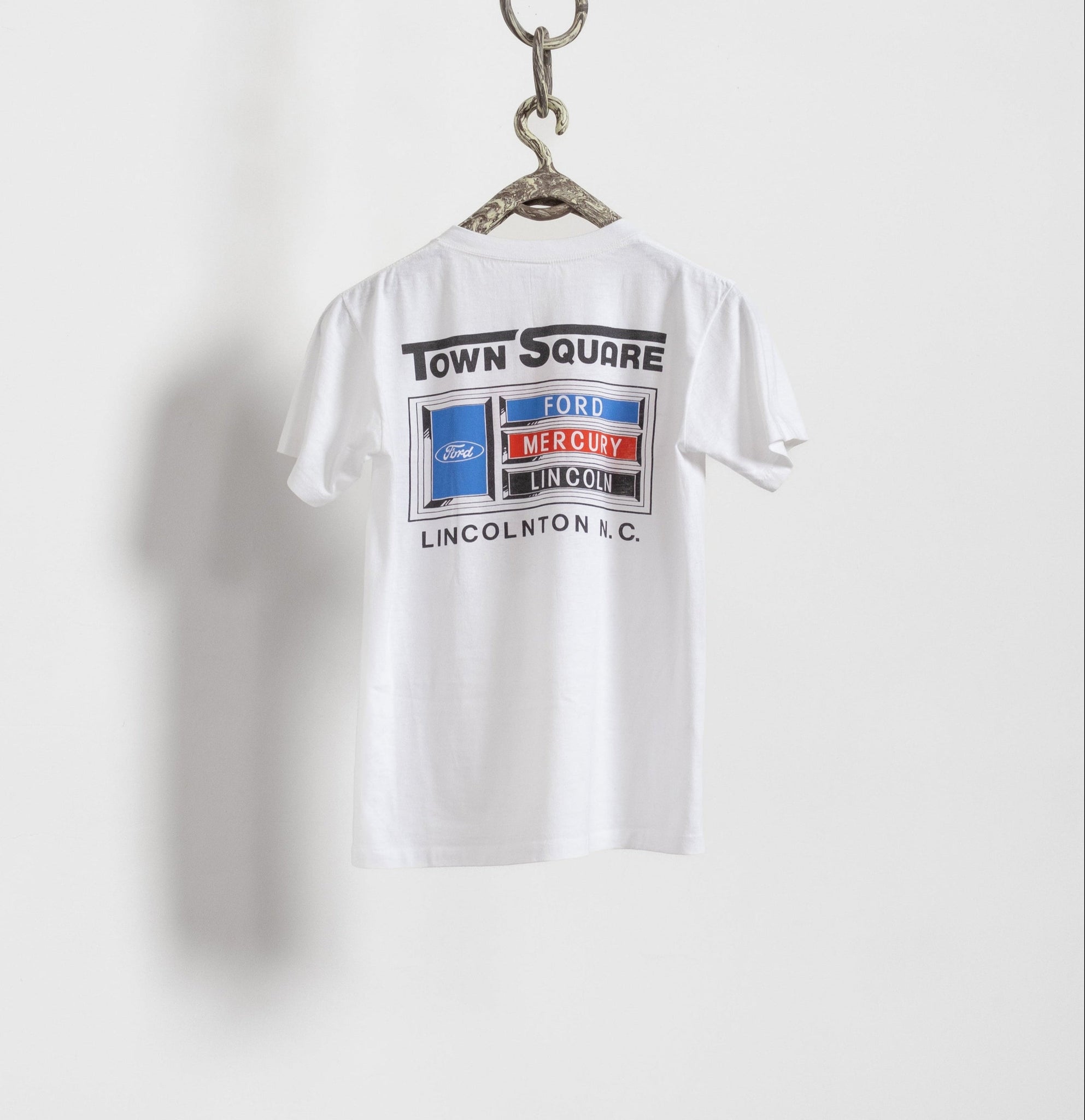 White t-shirt with graphic design on a hanger against a white background