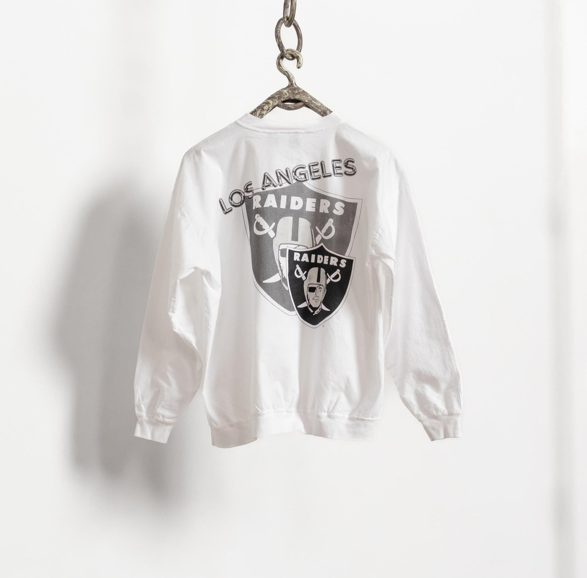 White bomber jacket with 'Los Angeles Raiders' logo on a hanger against a white background