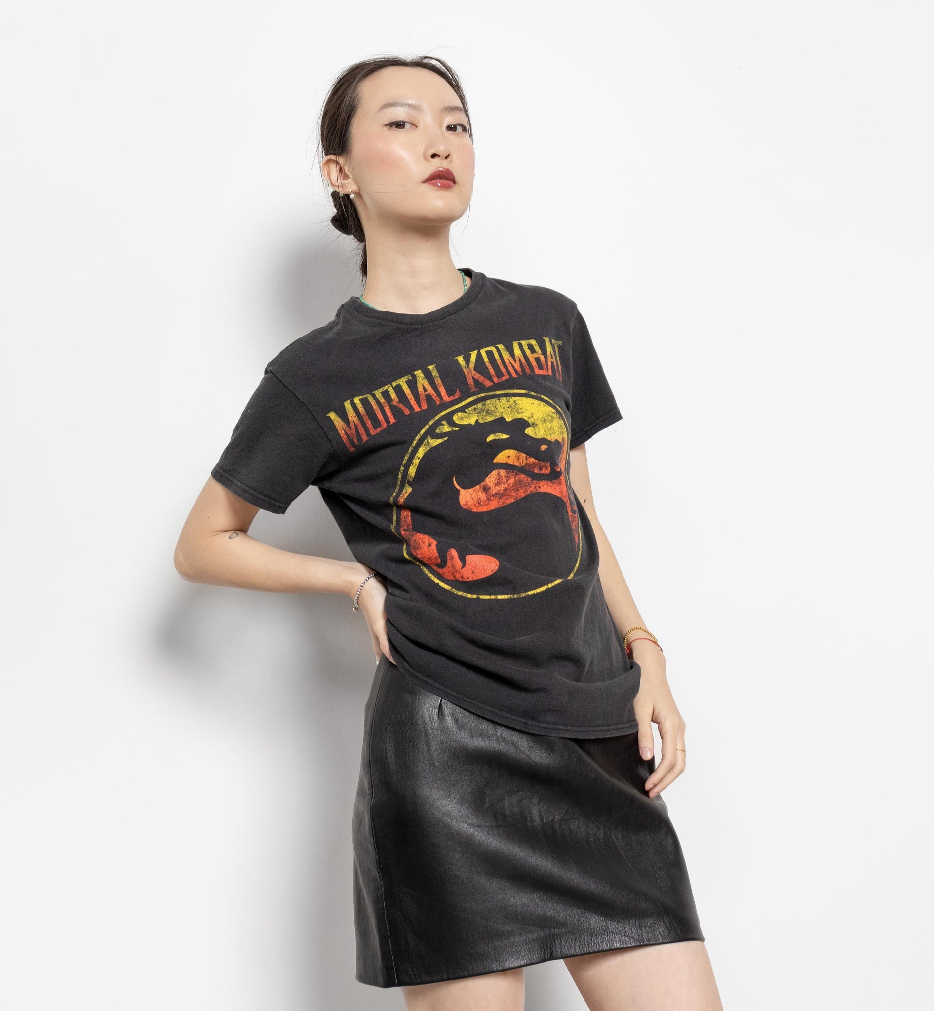 Person wearing a black 'Mortal Kombat' t-shirt with a logo on a white background