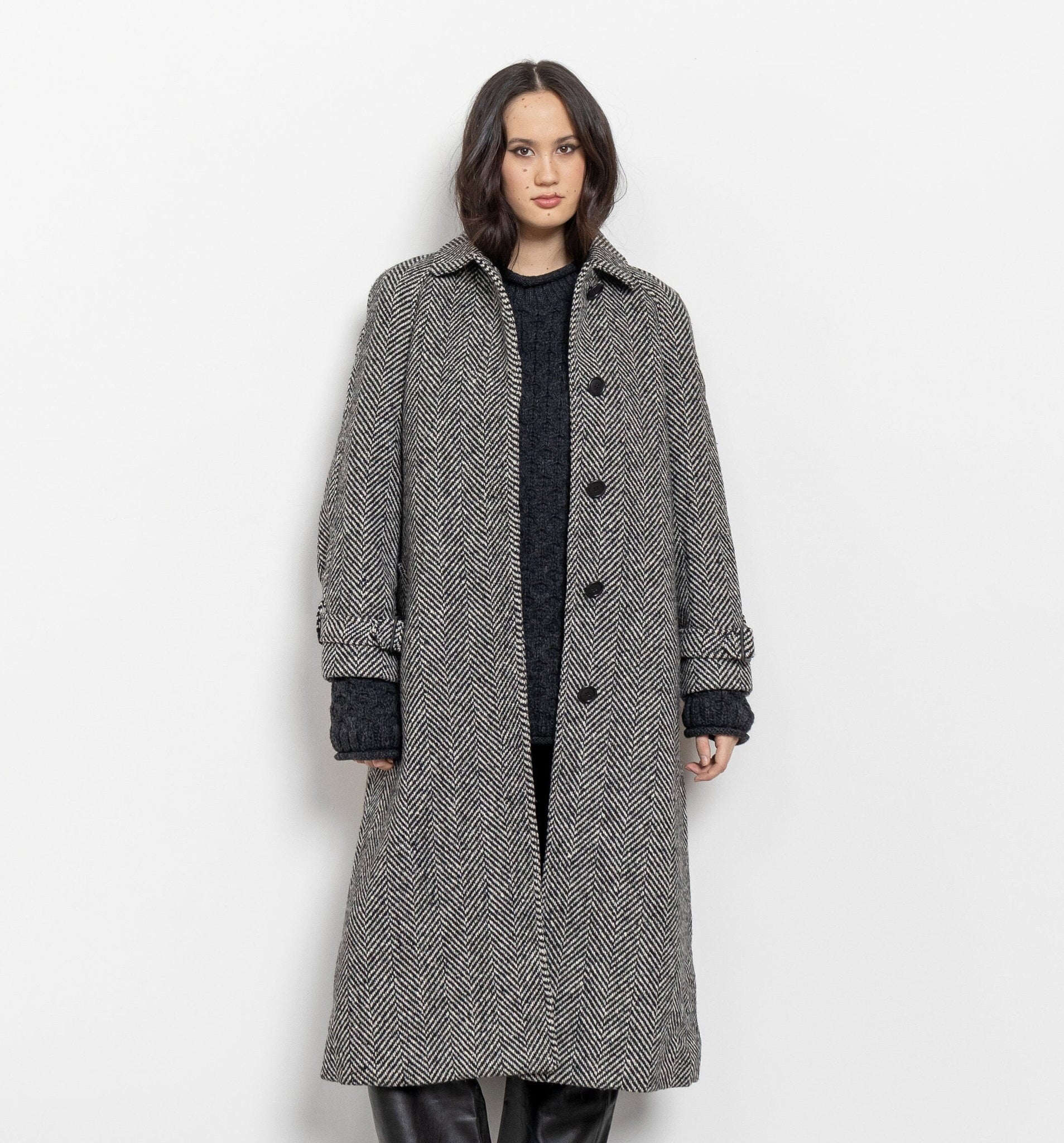 Person wearing a long gray coat on a white background