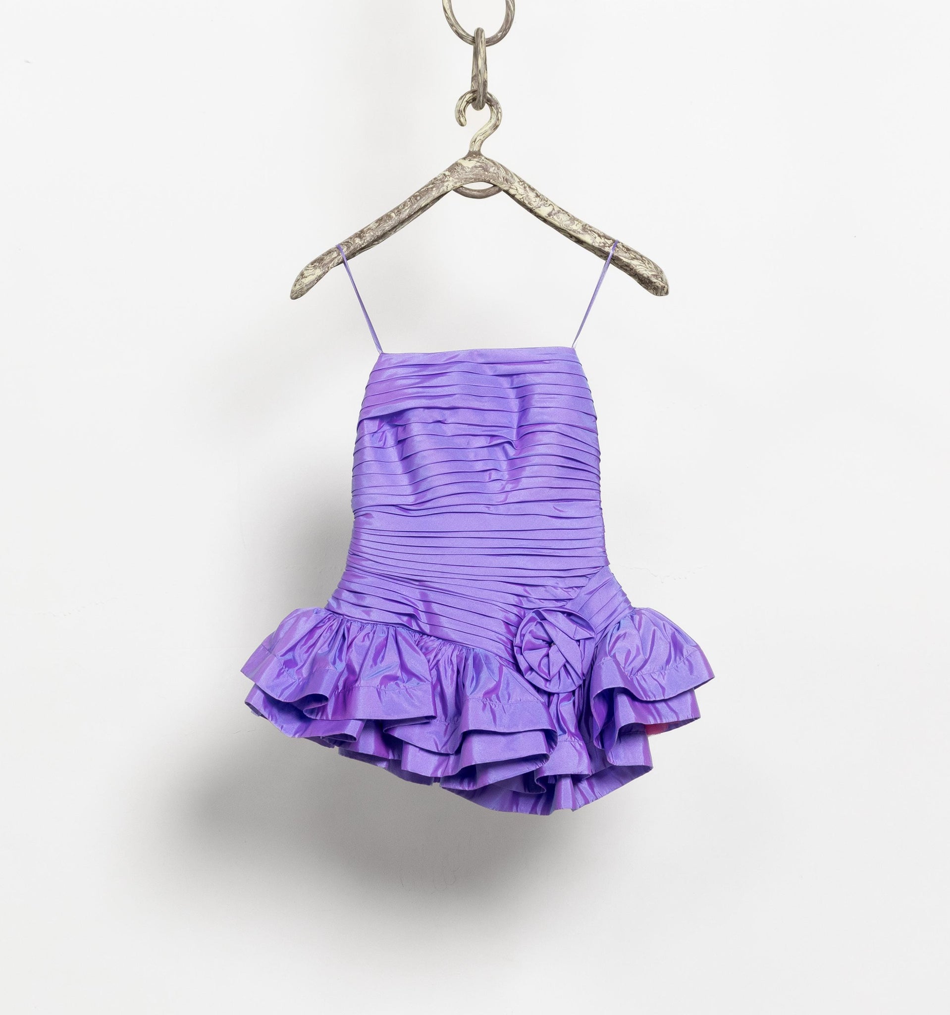 Purple ruffled dress on a hanger against a white background
