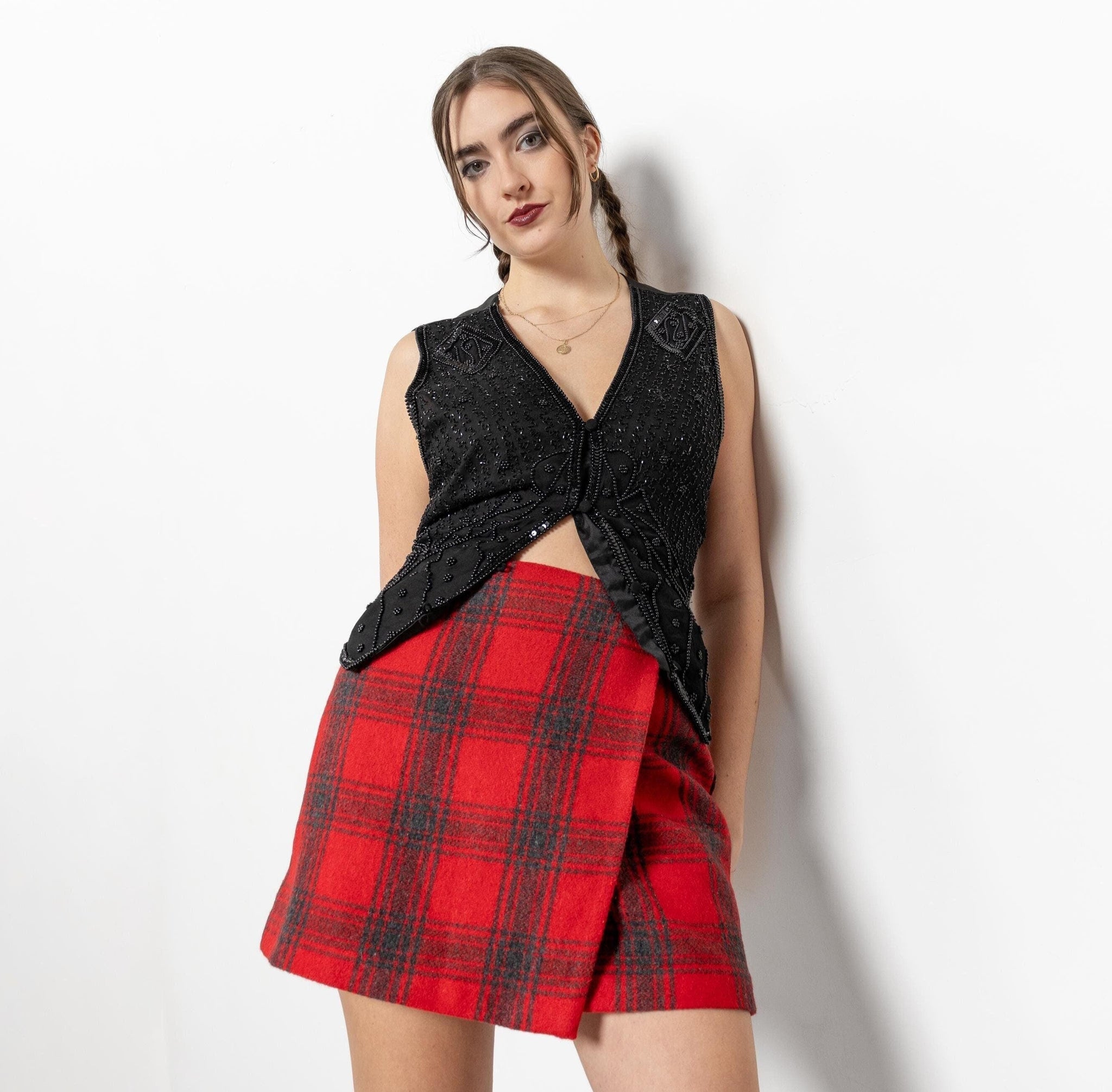 Woman wearing a black sleeveless top and red plaid skirt on a white background