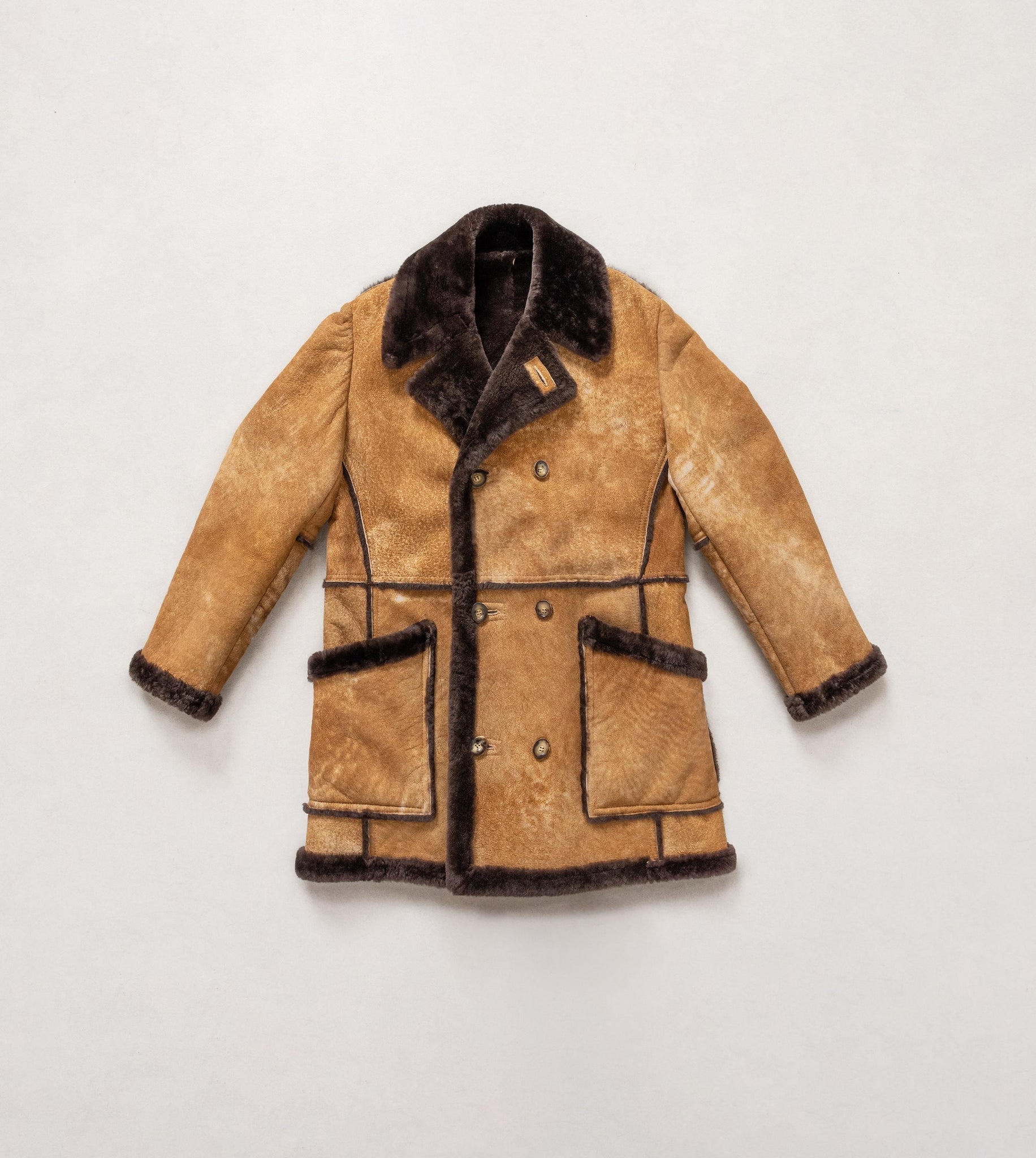 Brown shearling coat with dark fur trim on a light gray background