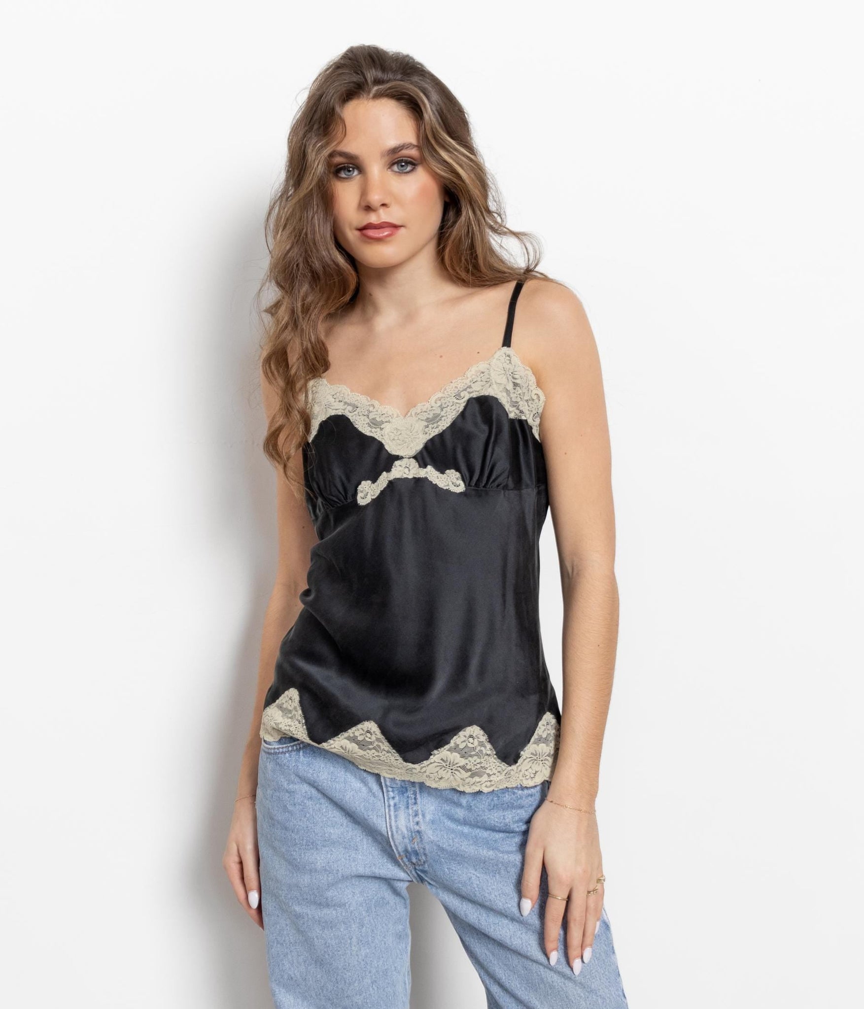 Woman wearing a black lace camisole and blue patchwork pants on a white background