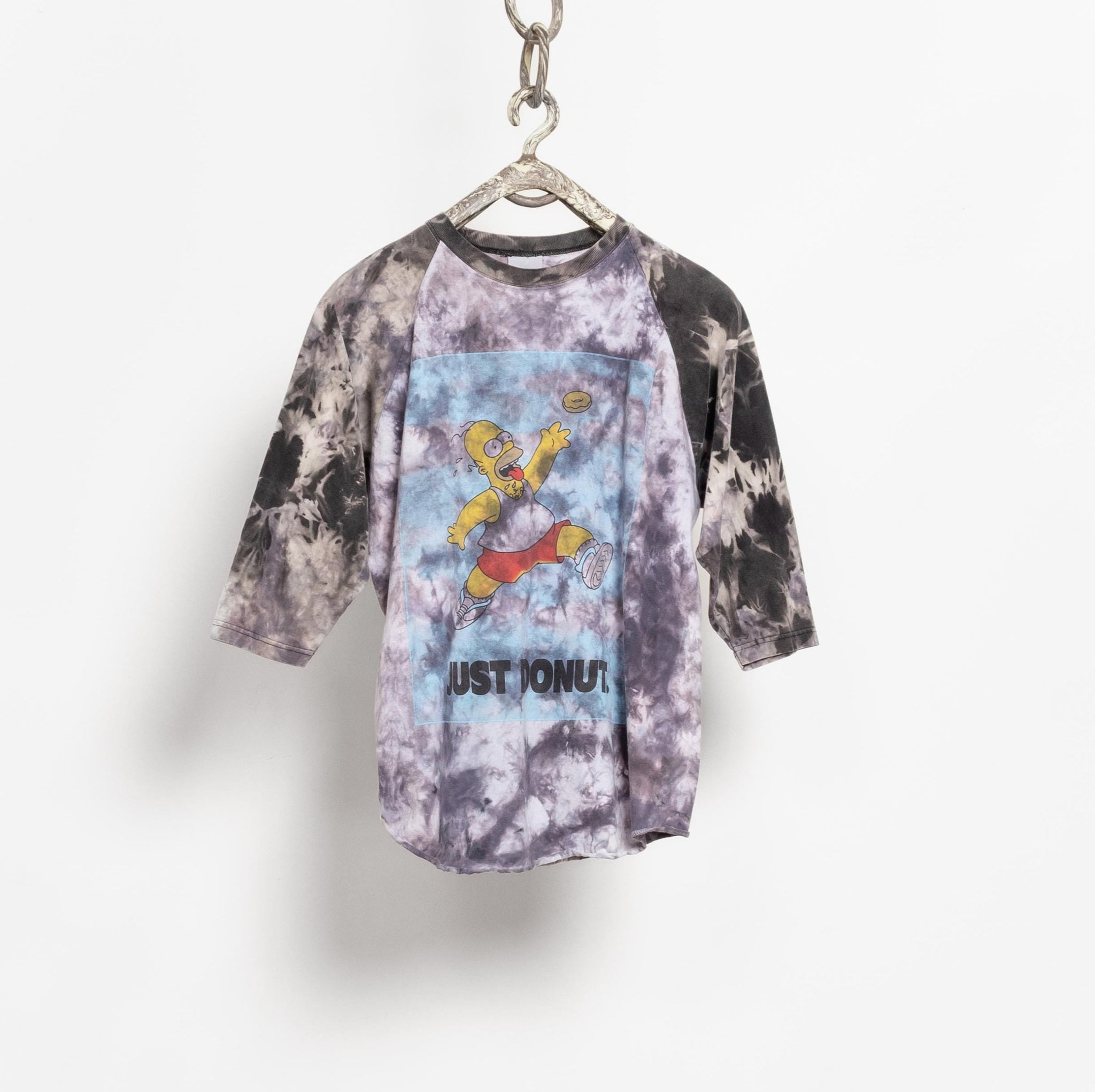 Tie-dye t-shirt with graphic design on a hanger against a white background