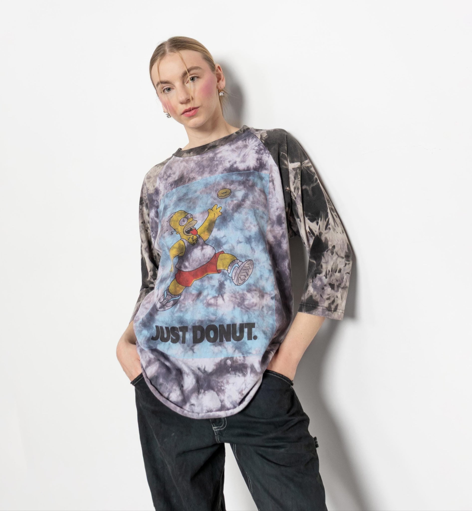Person wearing a tie-dye shirt with a graphic design and text on a white background