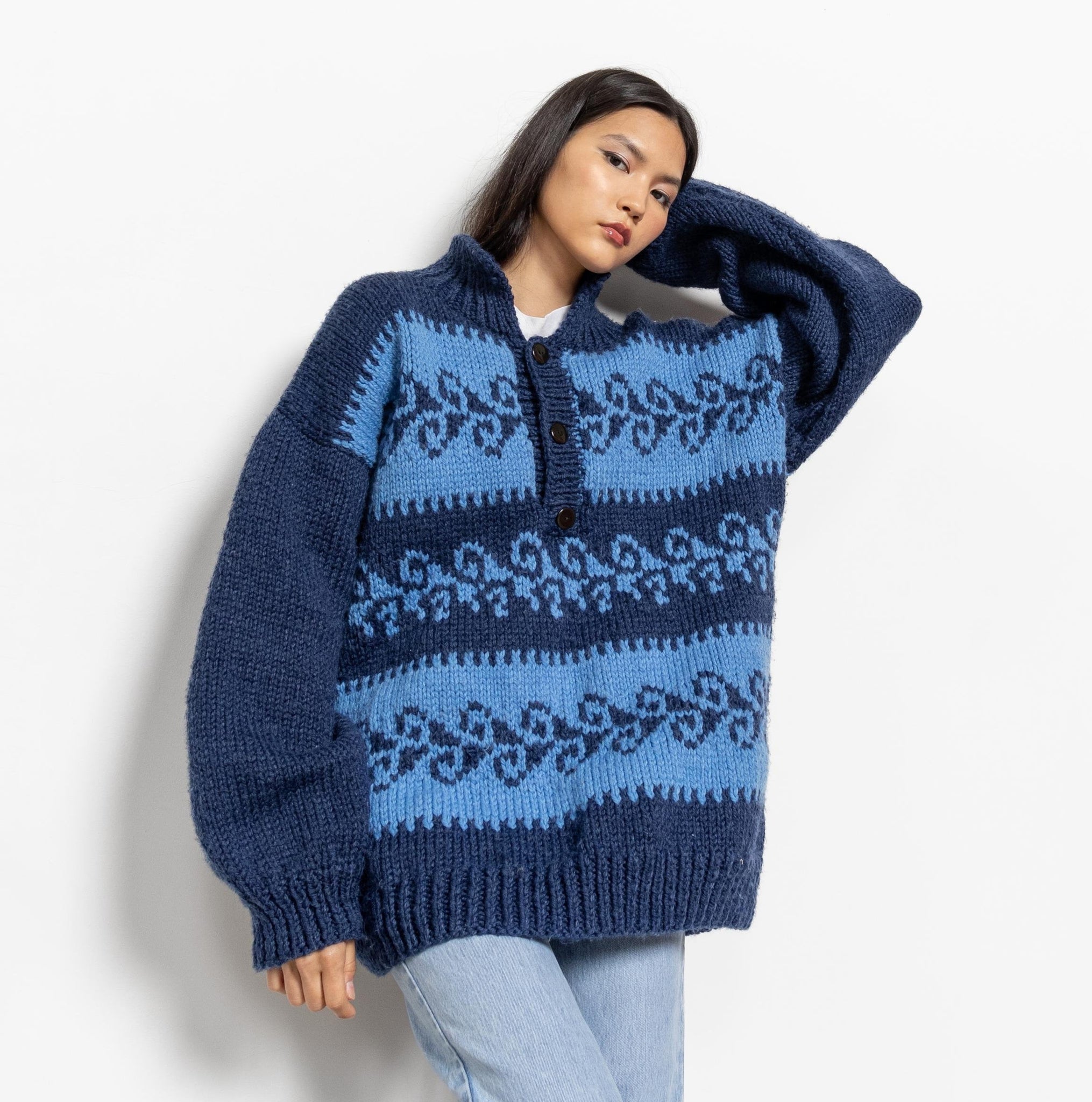 Person wearing a blue and navy patterned sweater on a white background